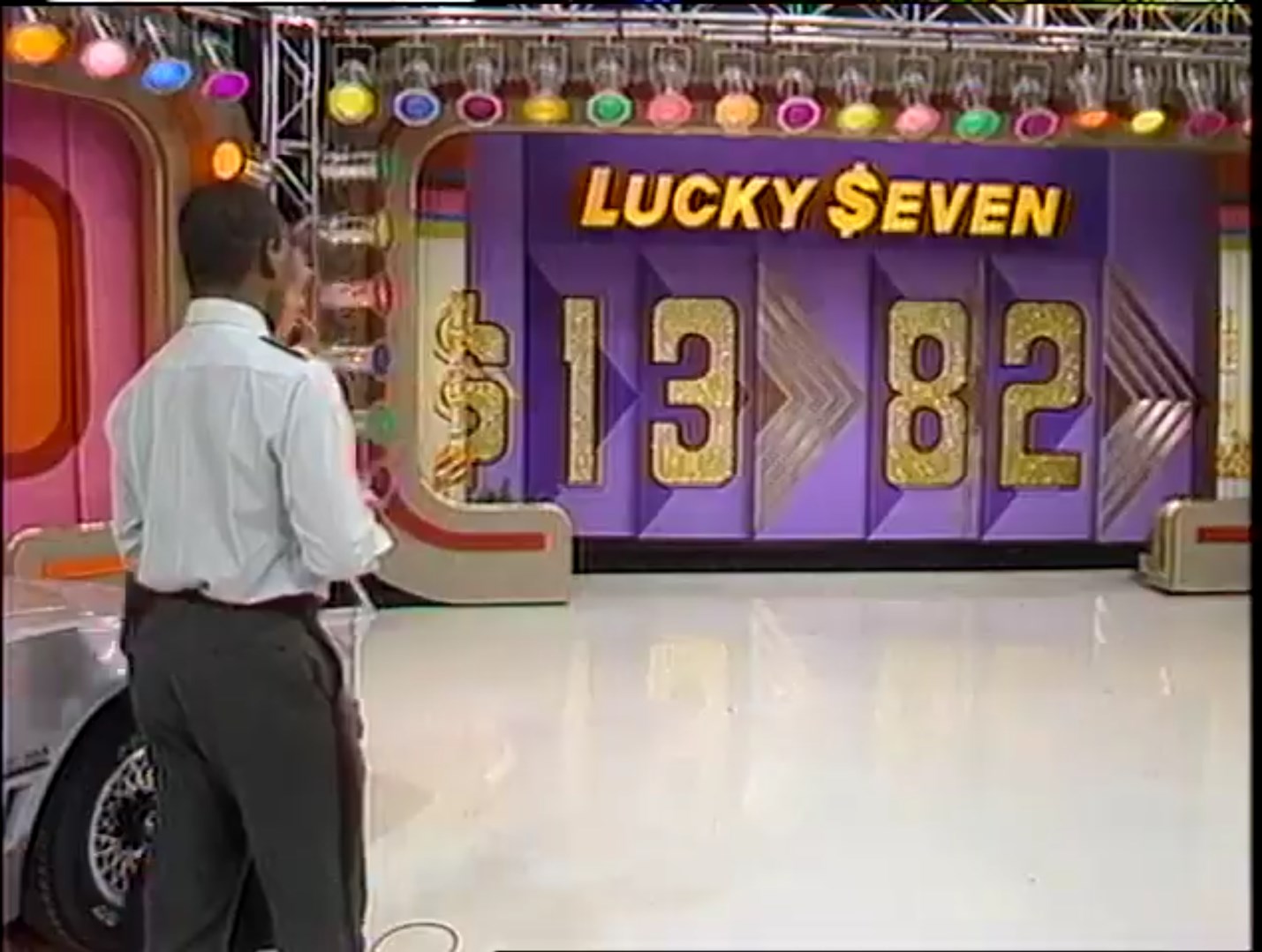 Contestant standing in front of the 'Lucky Seven' game board displaying the numbers 1, 3, 8, and 2 in a colorful studio.