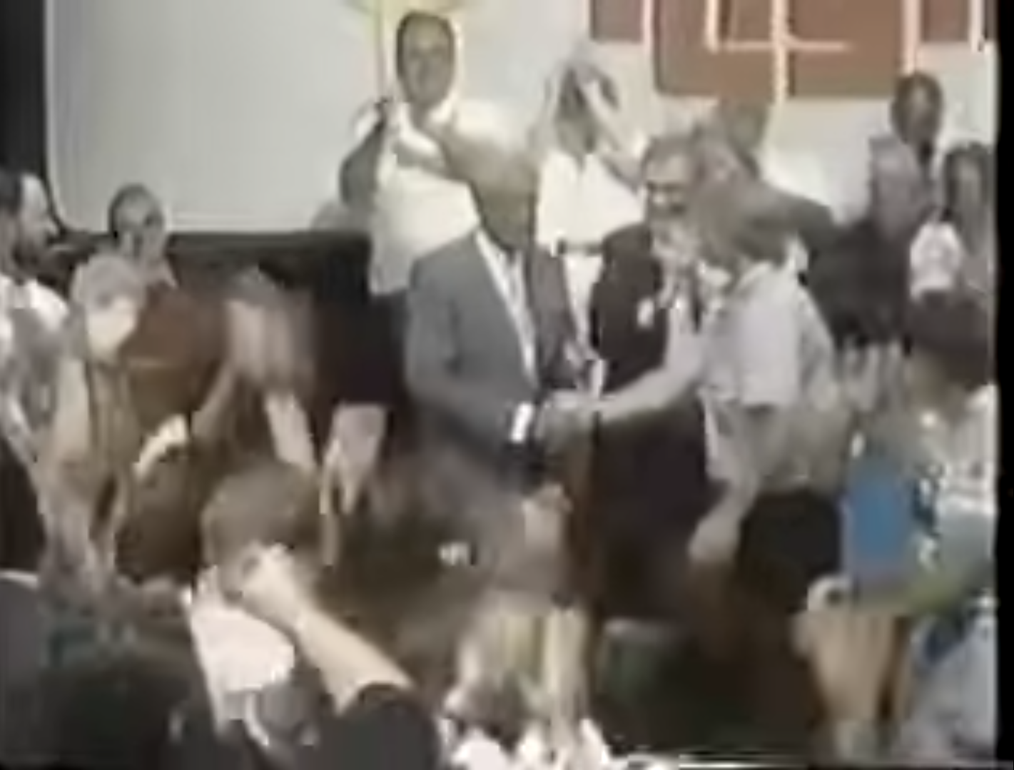 A lively audience cheering as a contestant shakes hands with the host during a game show segment.
