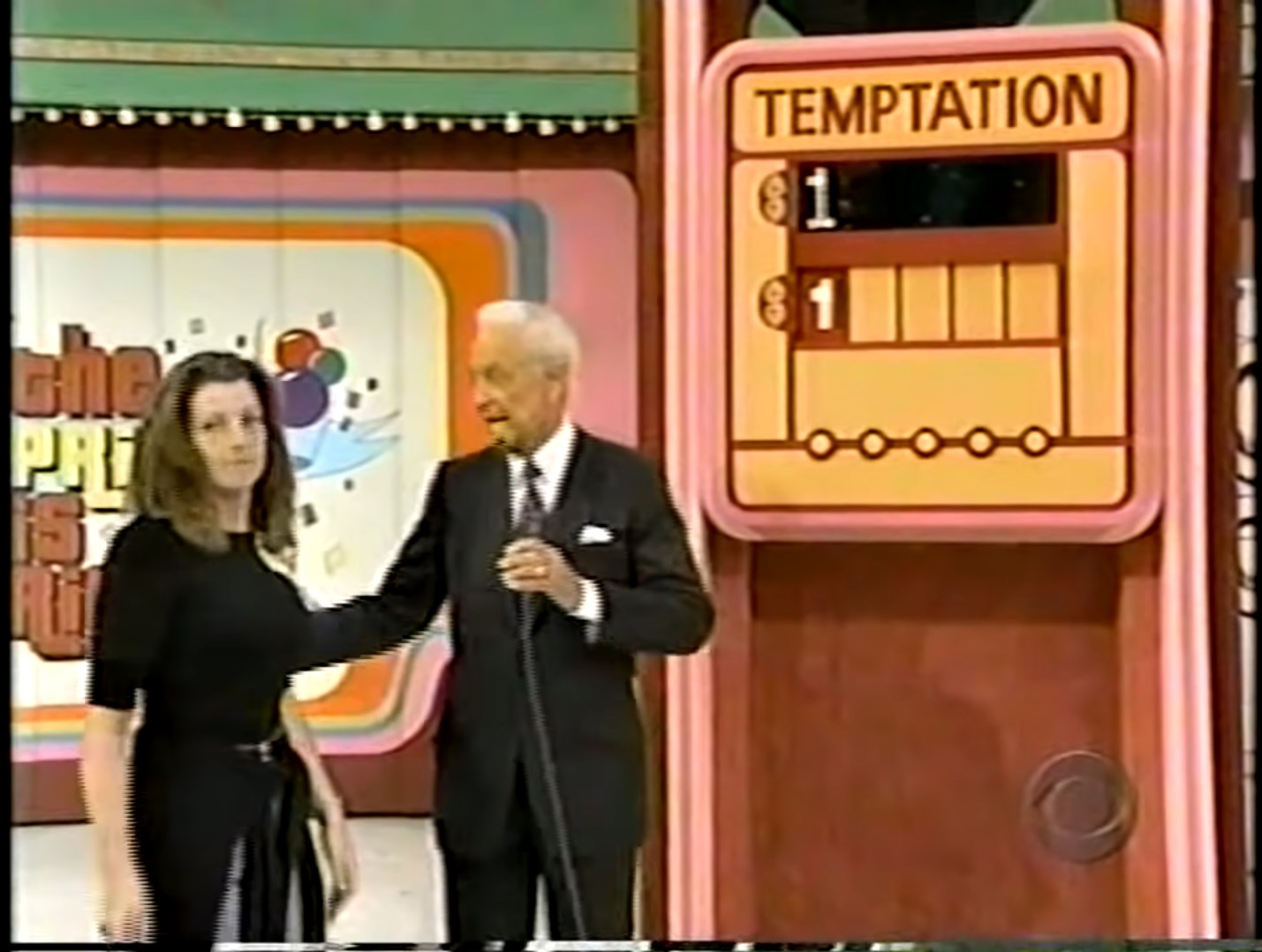 A contestant and host Bob Barker stand in front of the Temptation game board on 'The Price is Right', showcasing the game's branding and the current digit placeholders.