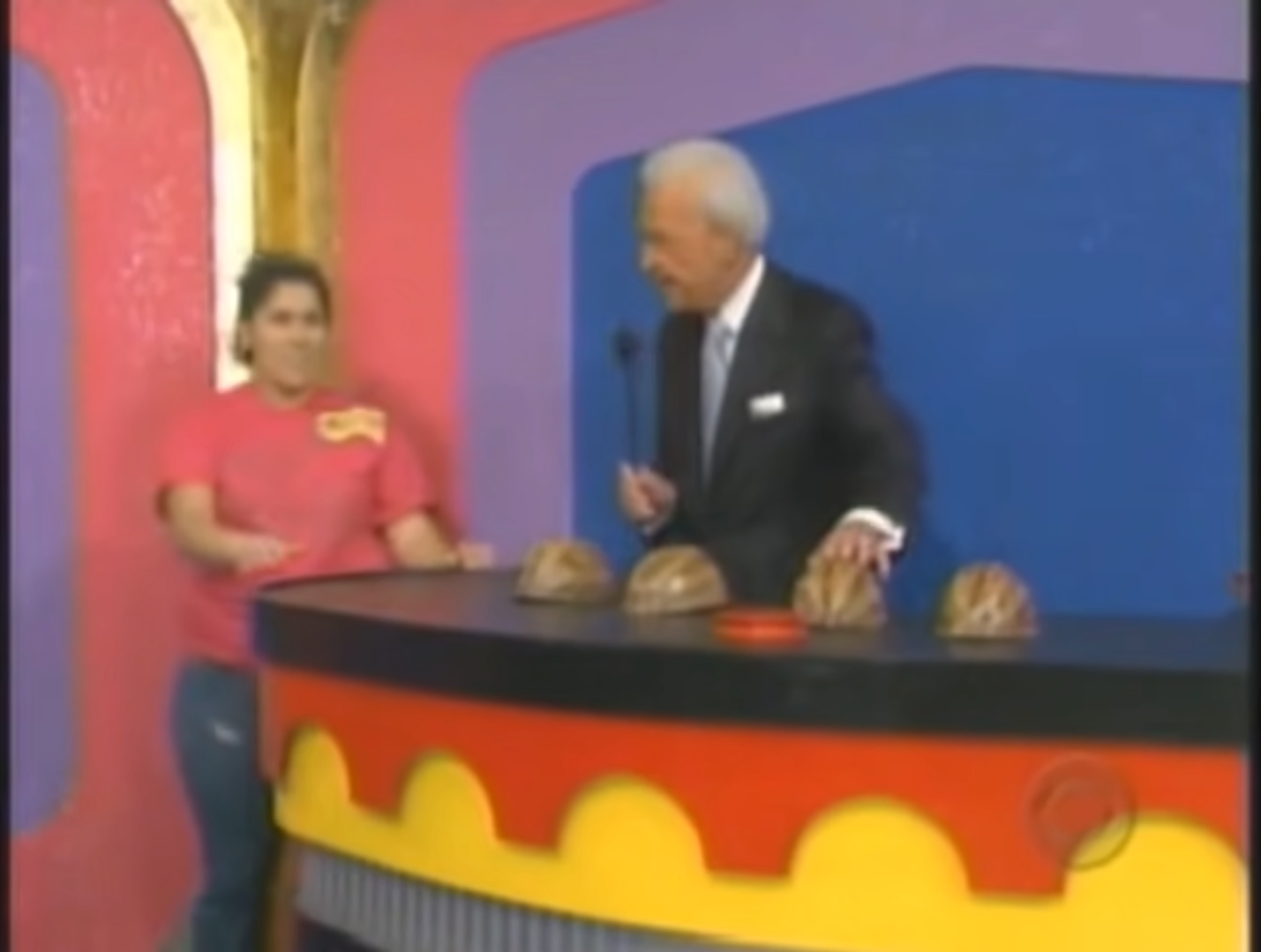 A contestant prepares to play the Shell Game on The Price is Right, with the host presenting four shells and a game board.