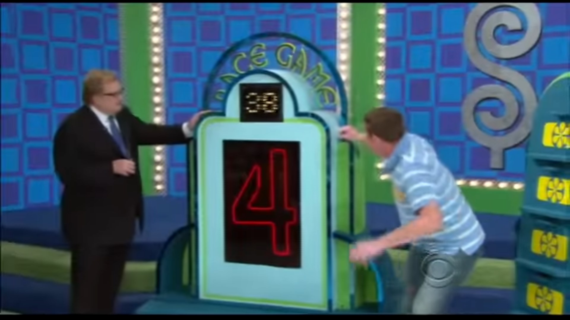 A contestant plays the Race Game on stage, with a visible timer showing '28' seconds and the number '4' displayed prominently. The host guides the contestant as they prepare to place price tags on prizes.