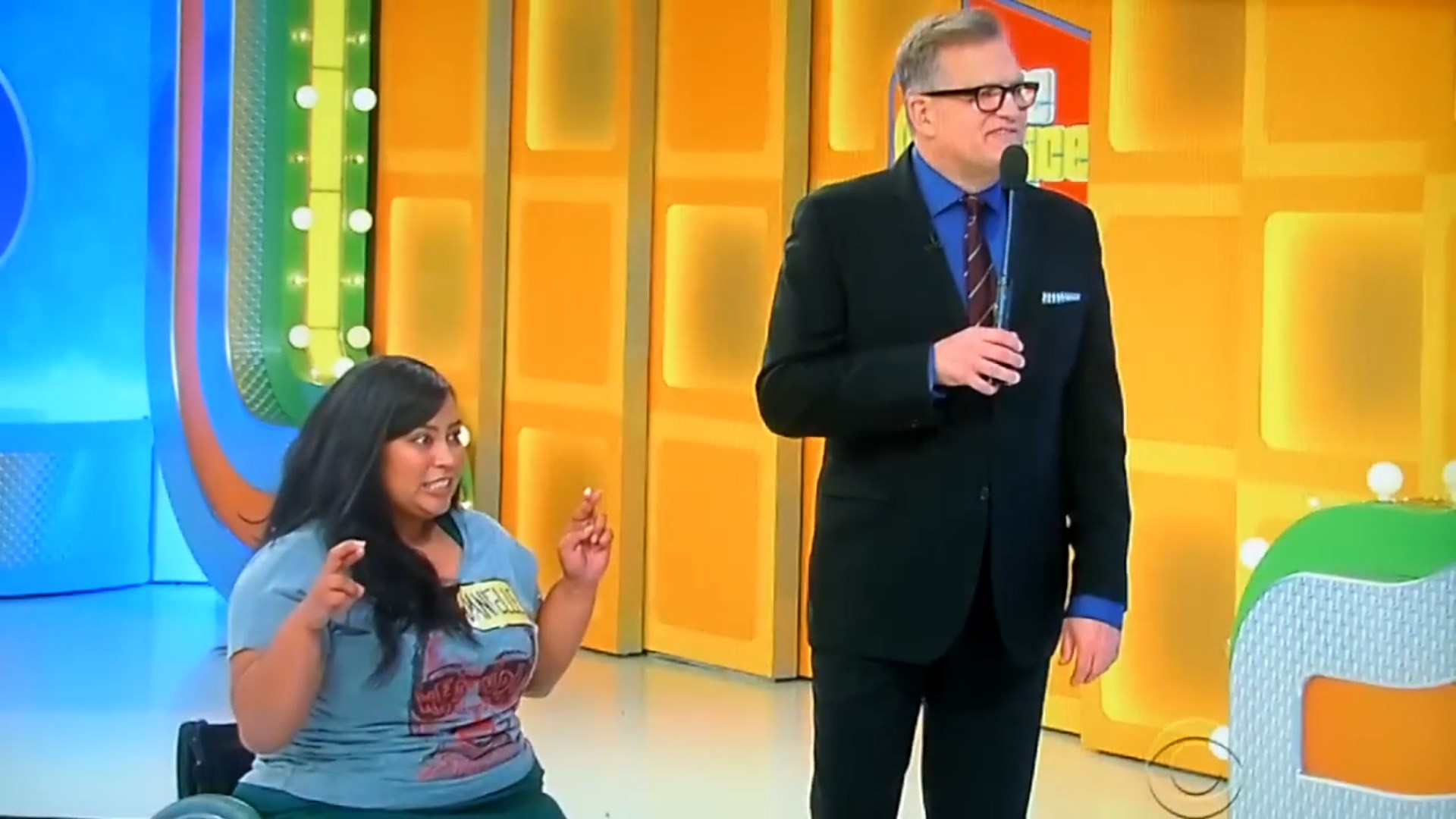 Contestant in a wheelchair reacting animatedly with a host at 'The Price Is Right' game show.