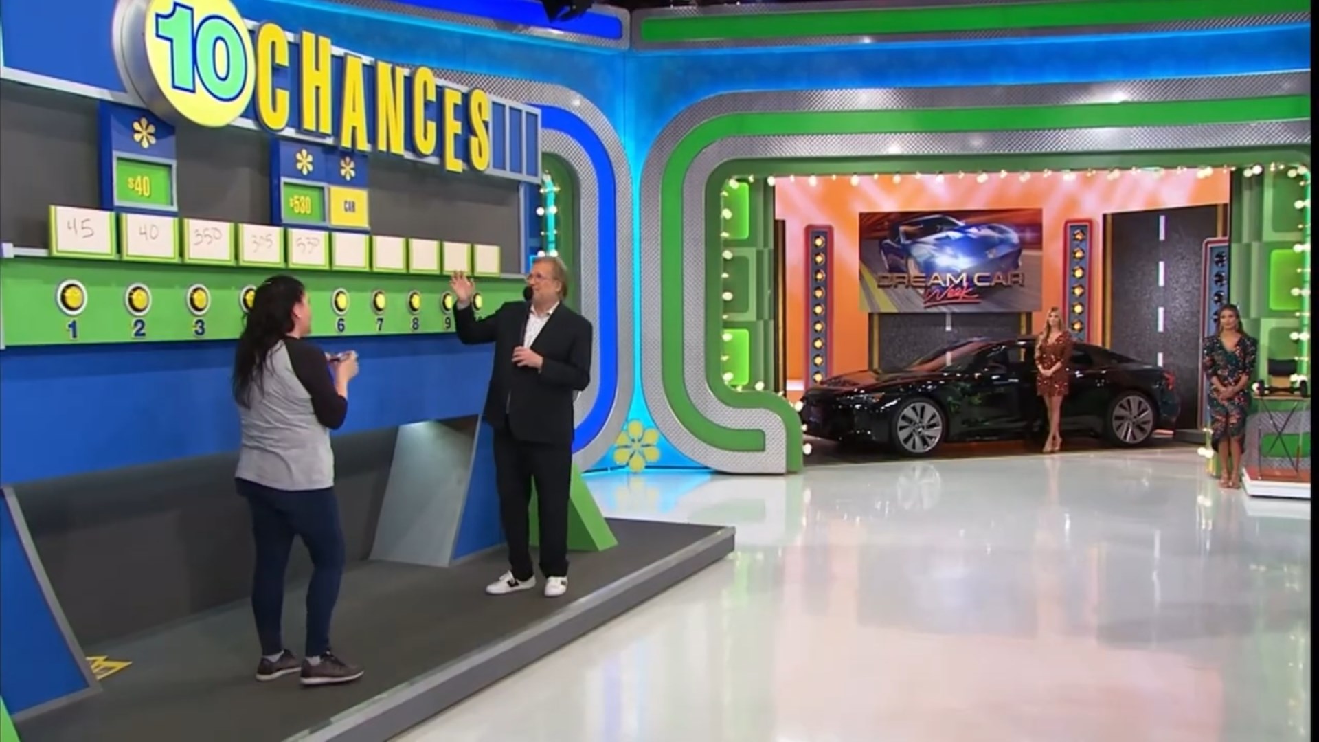 A contestant participates in the '10 Chances' game on The Price is Right, with a game board displaying price options and a black car in the background.