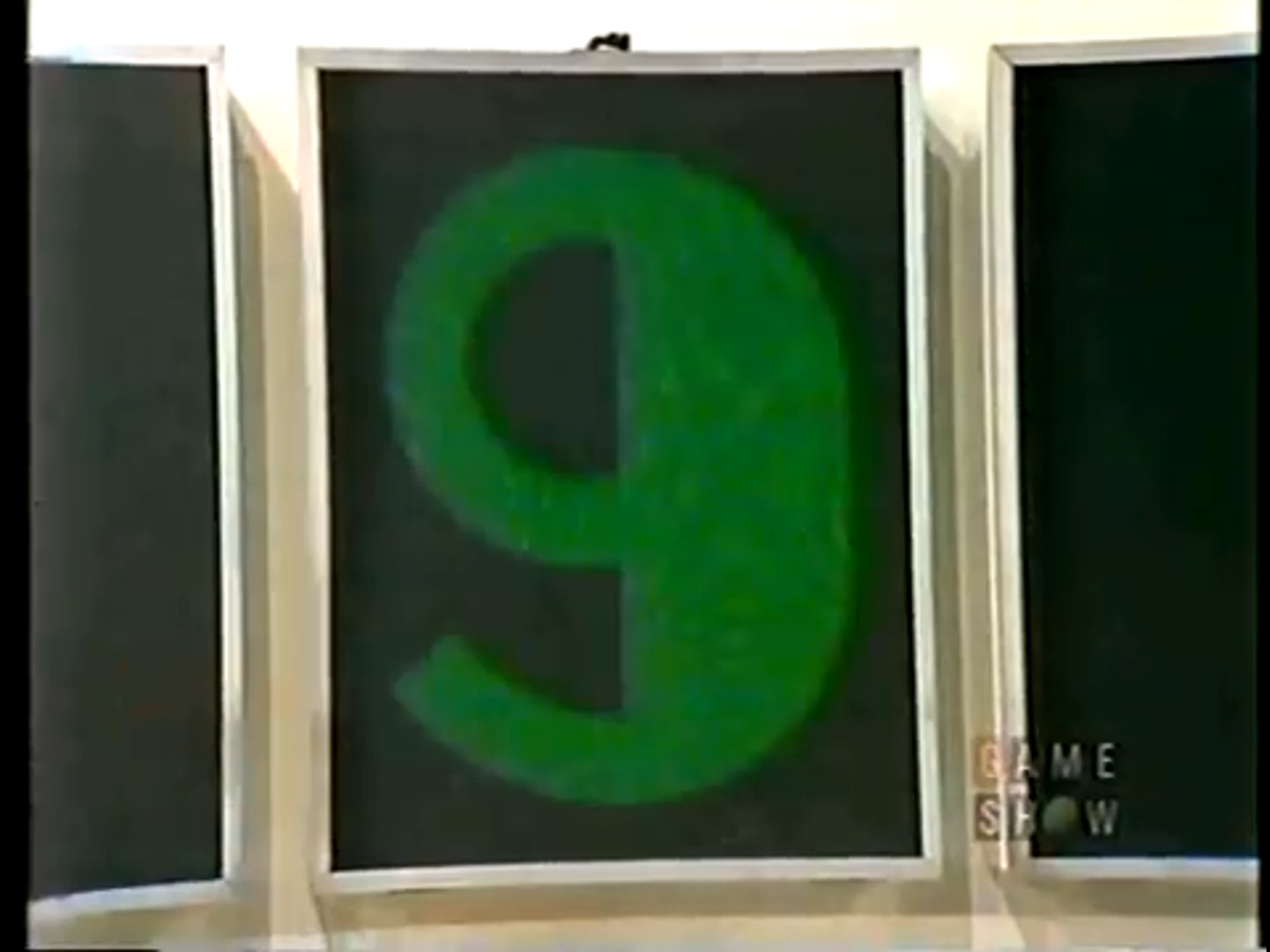 A large green number 9 displayed on a black background, flanked by two empty frames from a game show set.