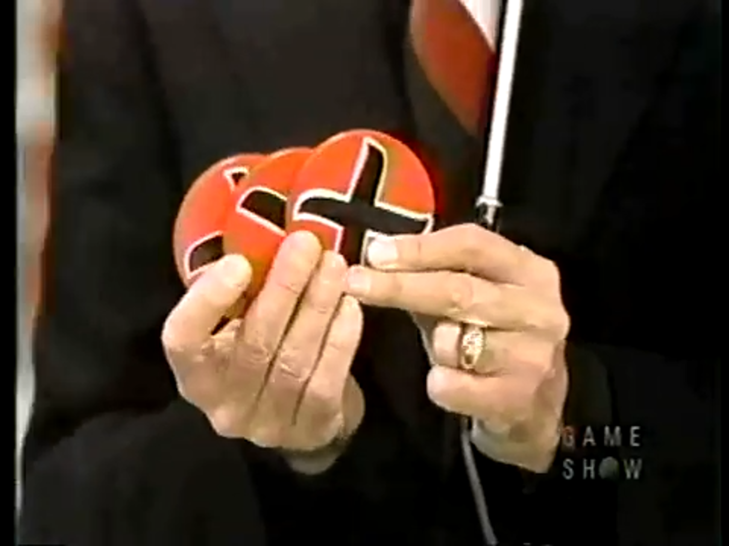 A hand holds three red strike chips with a black 'X' symbol, displayed against a blurred background.