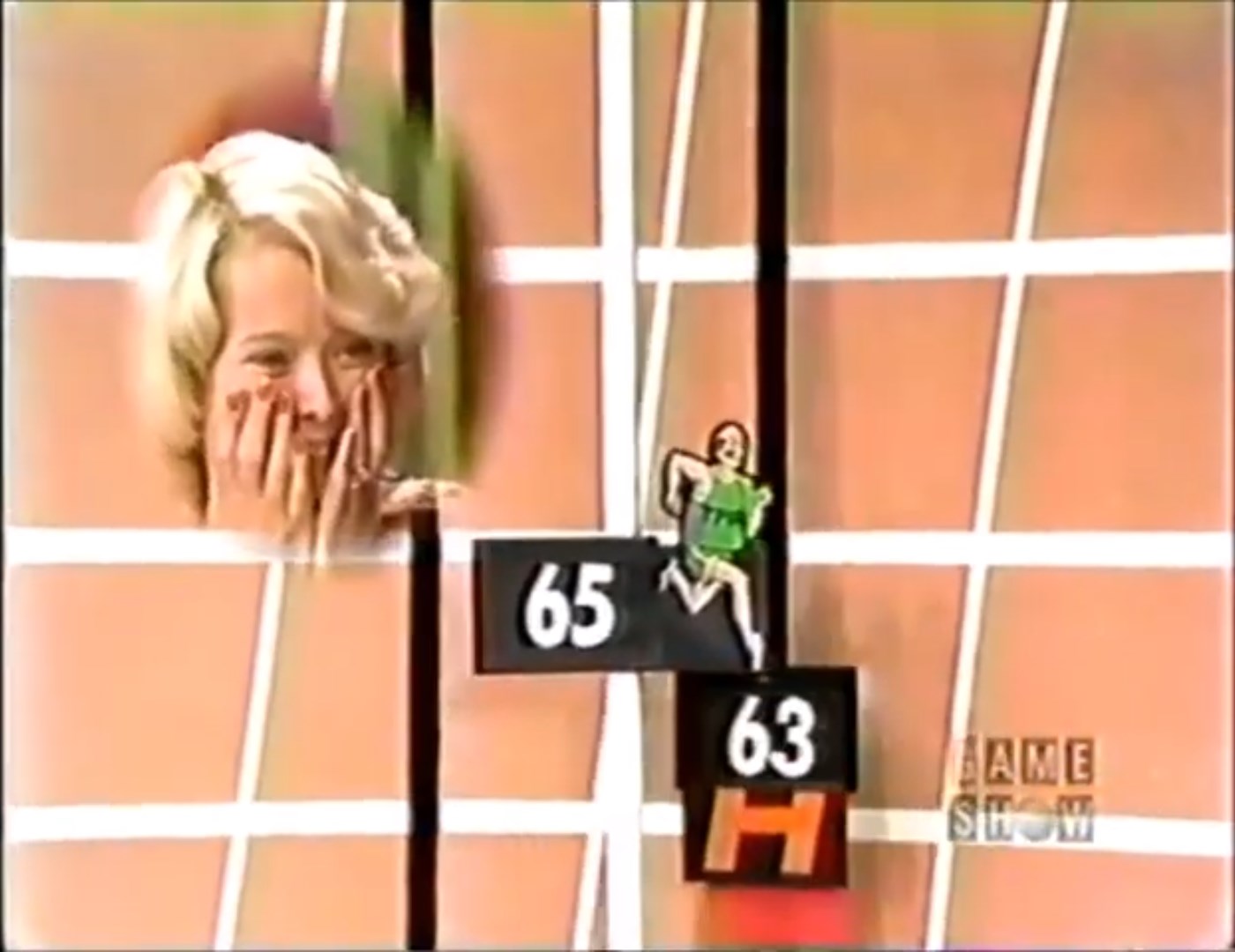 A contestant shows excitement with hands on their face as a cartoon runner approaches hurdles labeled with prices, during the game show segment Hurdles.