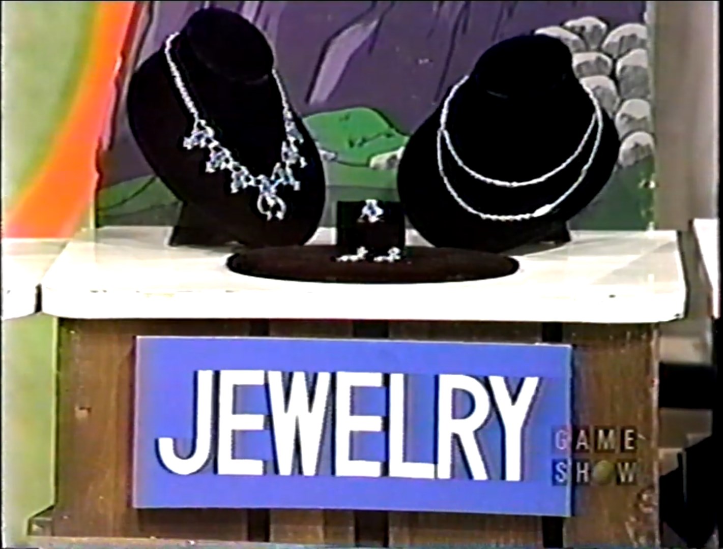 Display of jewelry including necklaces and earrings on a table with a blue sign reading 'JEWELRY'