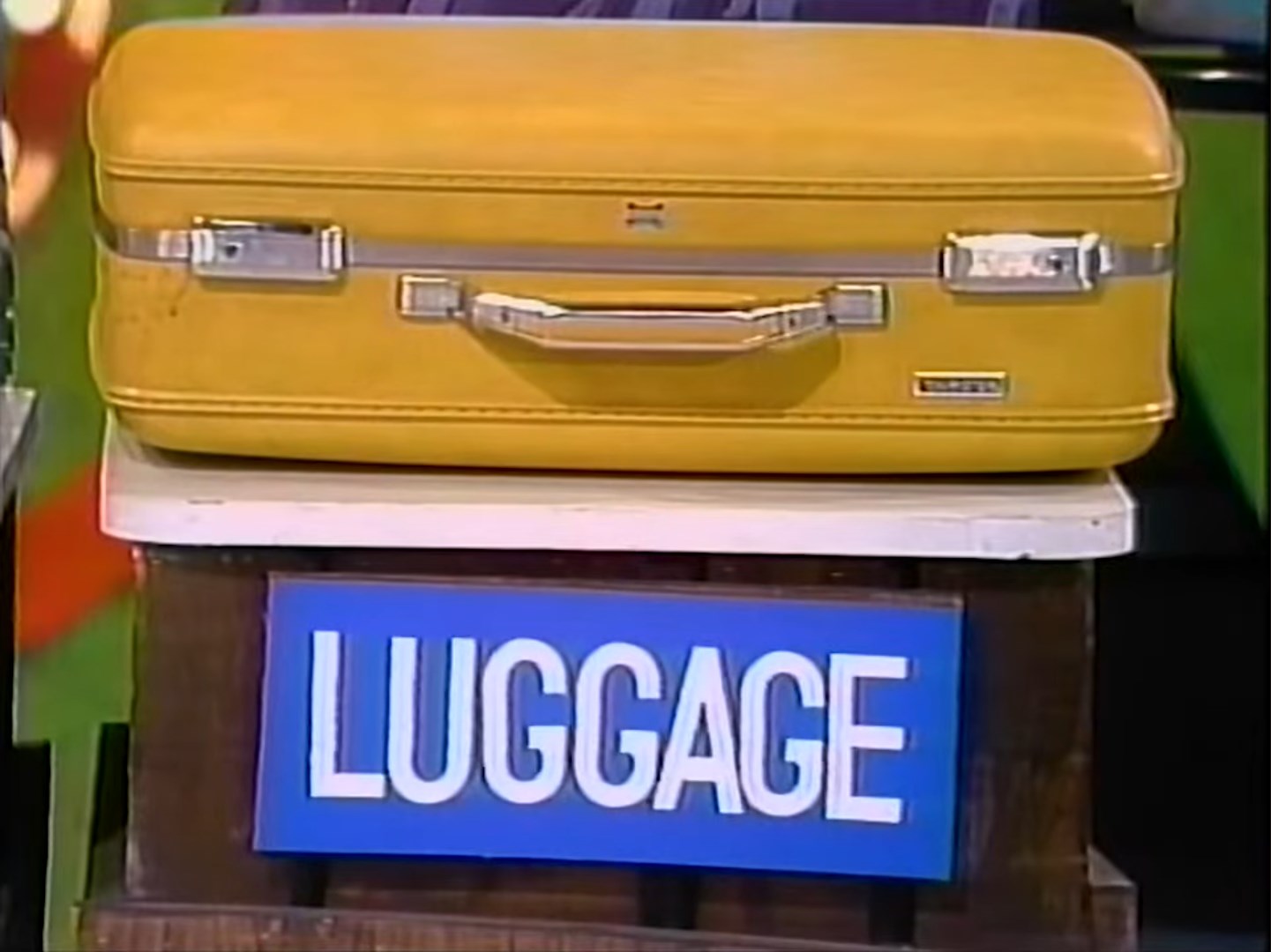 A yellow suitcase labeled 'LUGGAGE' displayed on a wooden stand.