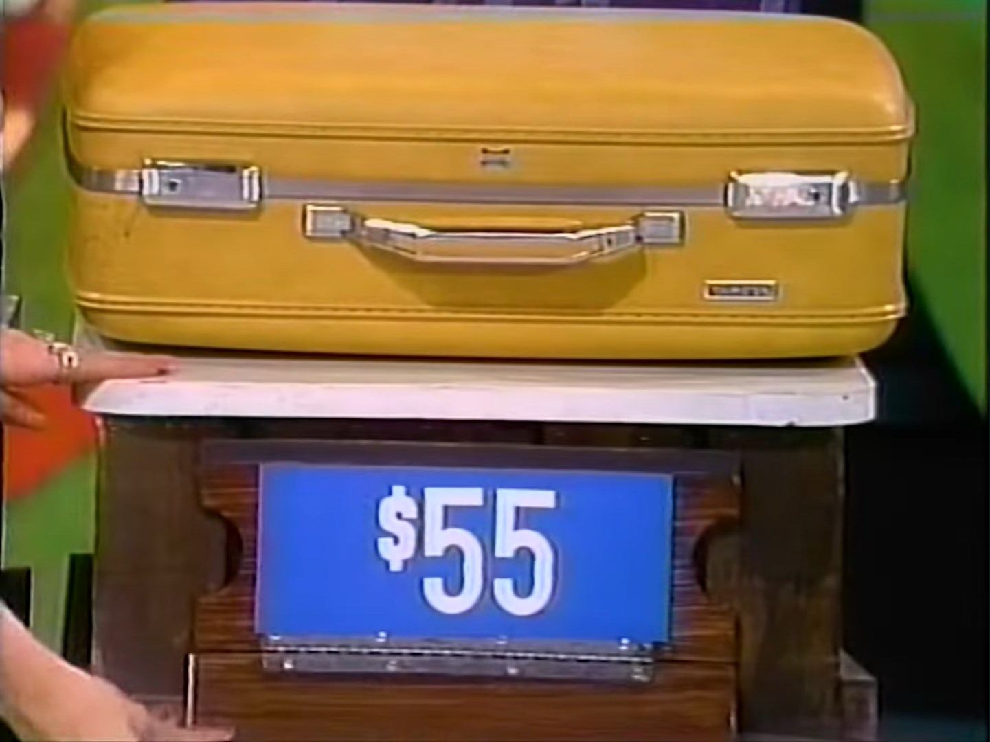 A yellow suitcase displayed on a table with a price tag reading .