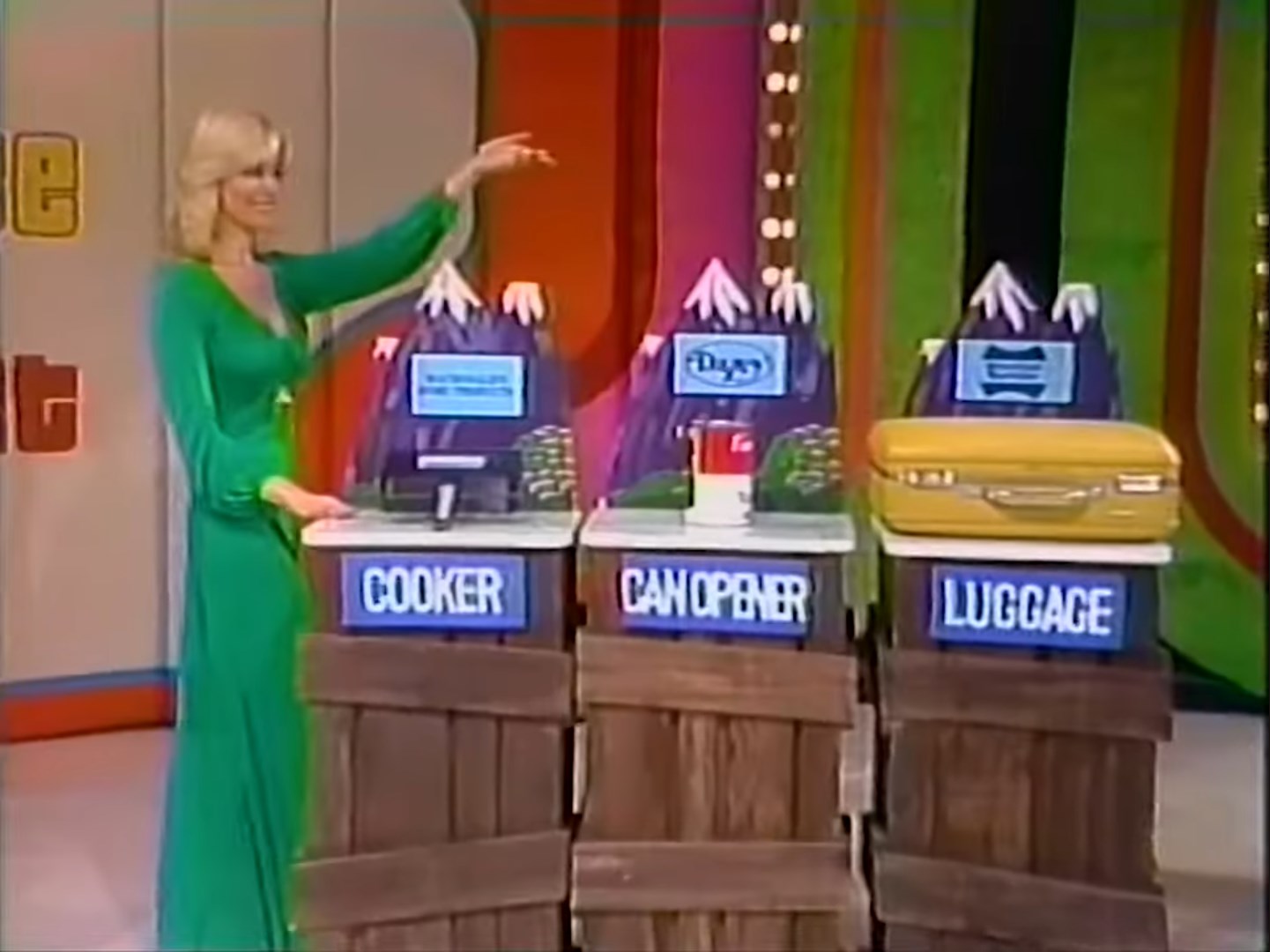Model presenting three small prizes labeled 'Cooker,' 'Can Opener,' and 'Luggage' in the game 'Cliff Hangers on The Price is Right in 1978.