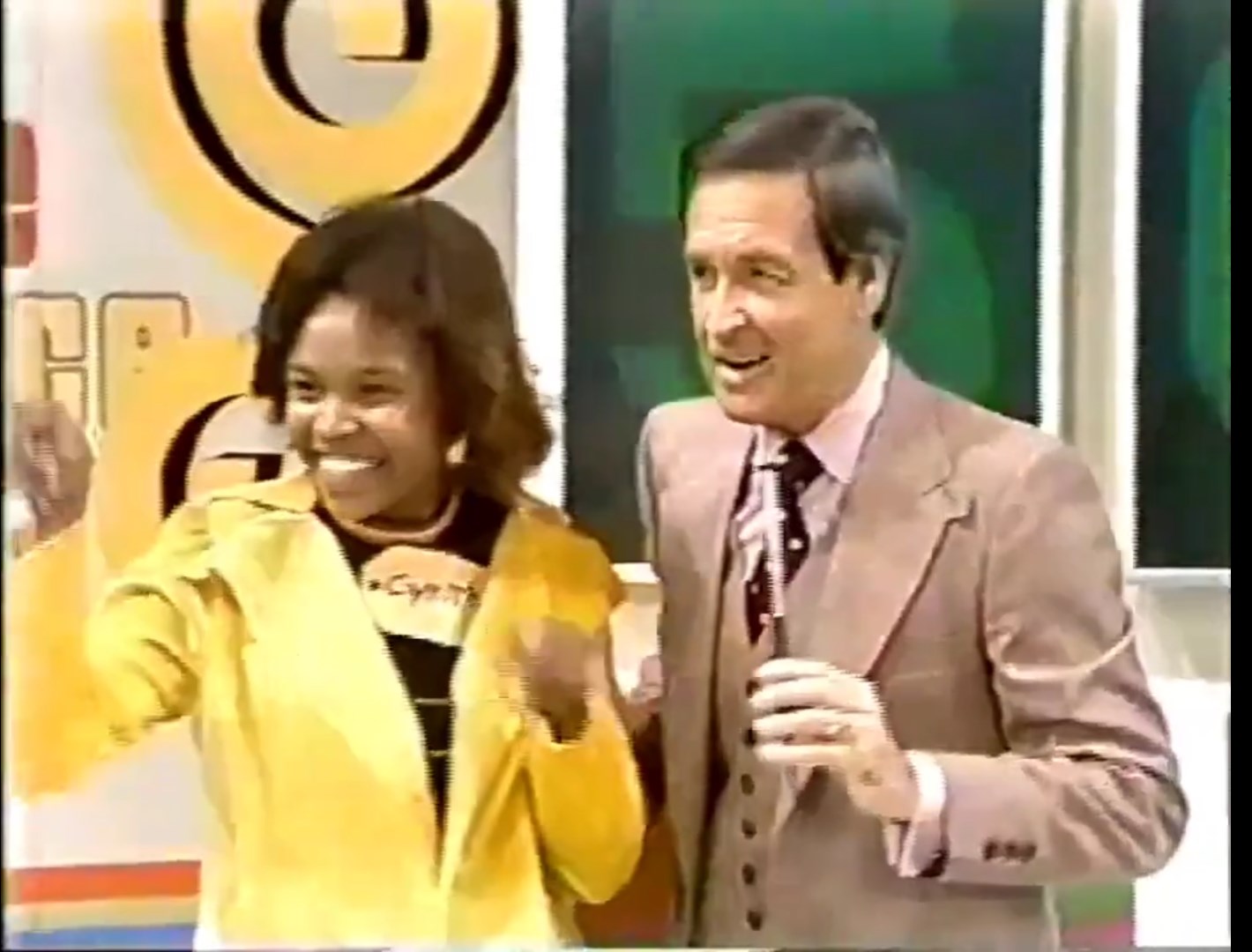 A contestant celebrating with enthusiasm alongside the host of a game show, both smiling and engaging with the audience, set against a colorful game show backdrop.