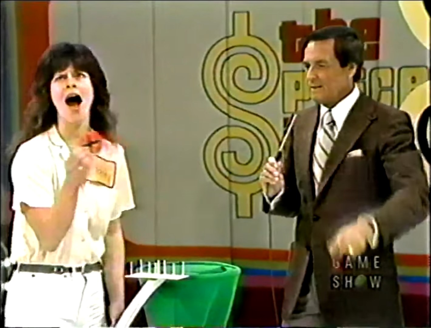 A contestant excitedly holds up a chip while talking to the host during a game of Three Strikes on The Price is Right.