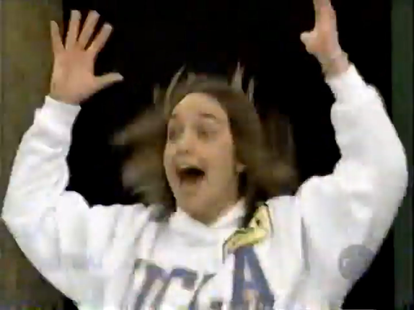 A contestant joyfully reacting with raised hands, wearing a white sweatshirt with 'UCLA' printed on it.