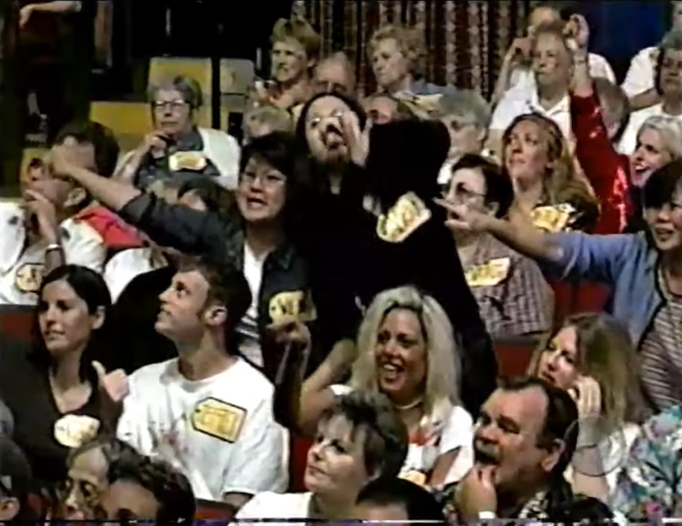 Audience members enthusiastically participating during a game show, with visible price tags on their clothing.
