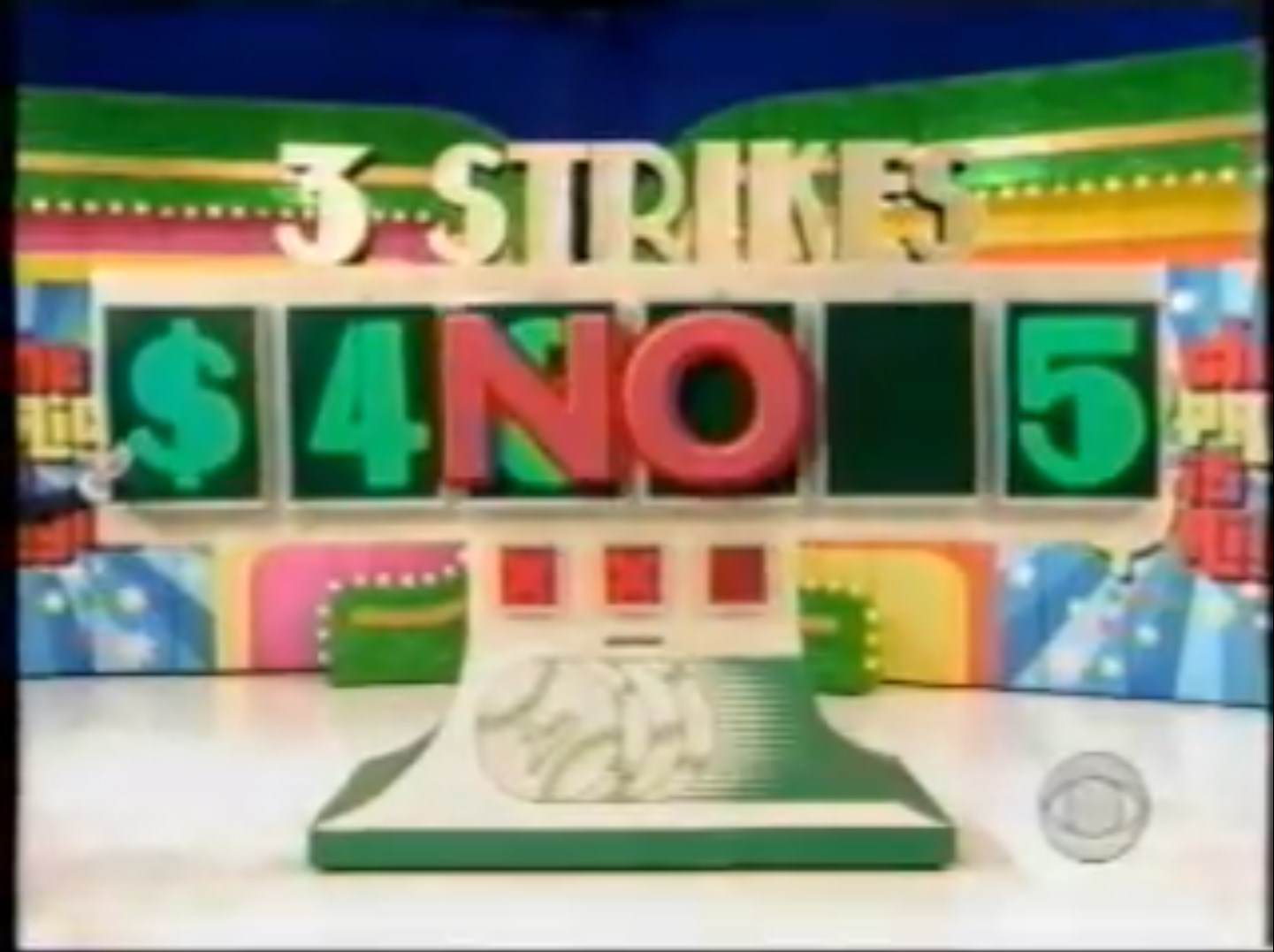 A Three Strikes game display showing the numbers , NO, and 5 with a green background while a host gestures towards it.