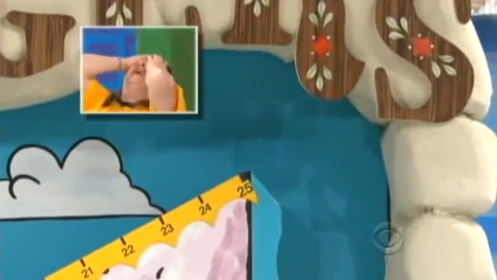 A contestant in a yellow shirt with their hands on their face expresses distress as the game's mountain climber approaches the edge of a cliff on a colorful game board.