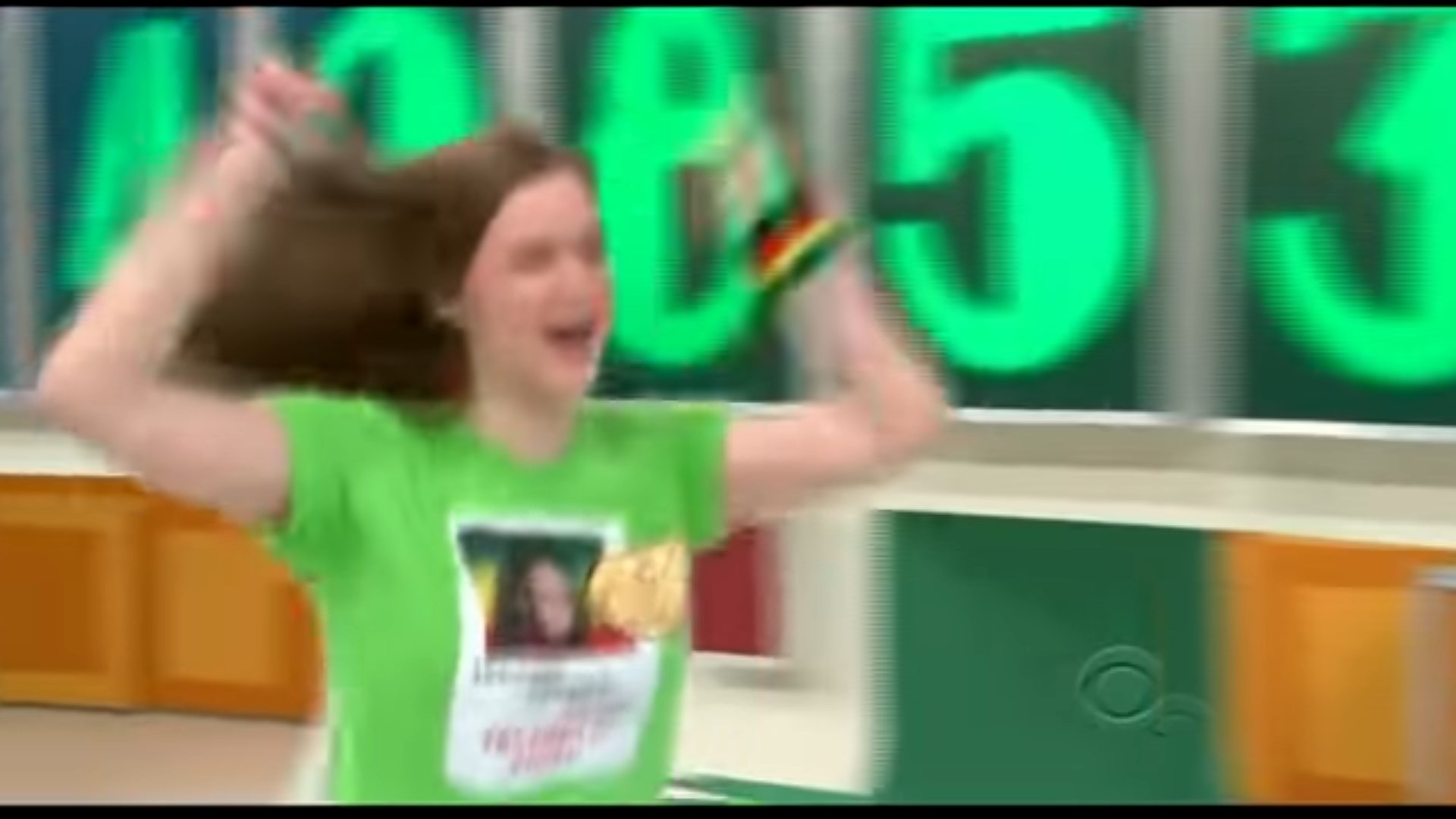 A contestant celebrates enthusiastically while holding their arms up in excitement after having won an electric car on Three Strikes.