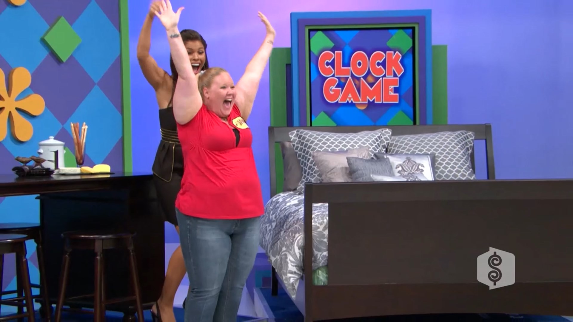 A contestant celebrating enthusiastically during the Clock Game segment on a game show, with a bed set displayed in the background.