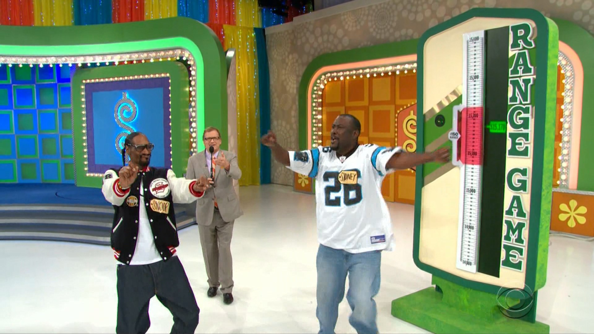Snoop Dogg and a contestant celebrate in the Range Game set, with the prize scale prominently displayed in the background.