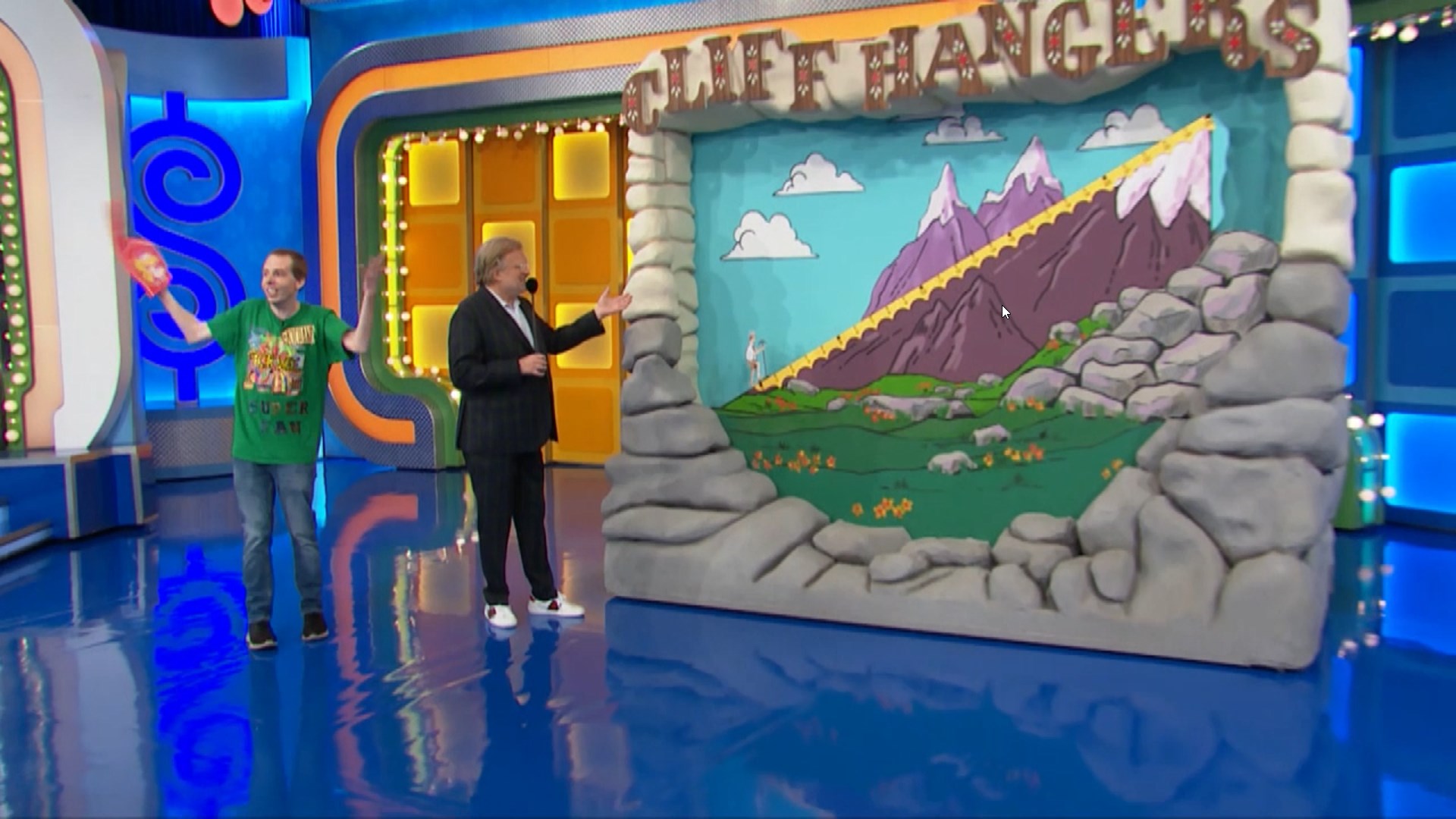 A colorful set for the game 'Cliff Hangers' on The Price is Right, featuring a cartoon mountain, a mountain climber, and bright blue background.