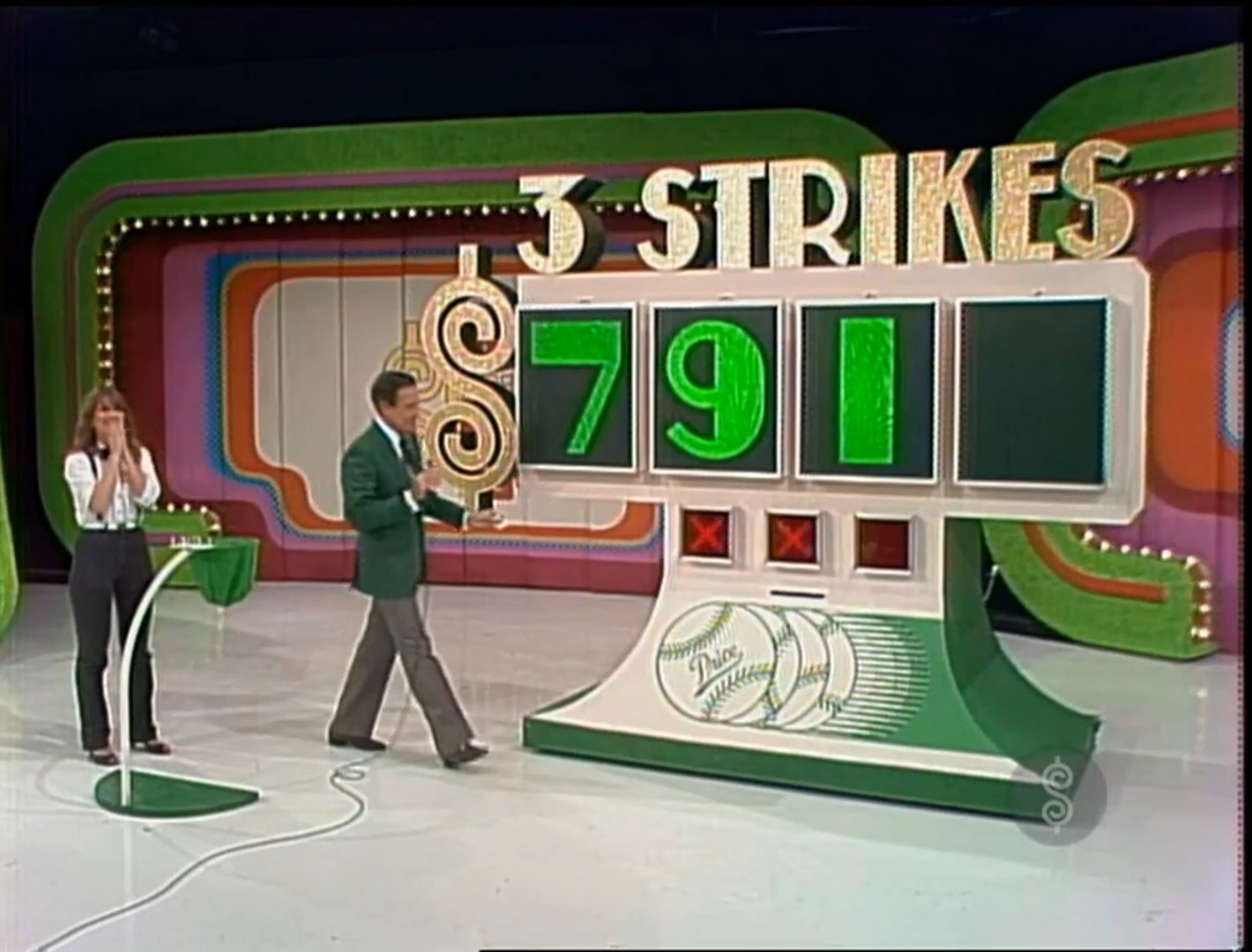 A contestant and host reveal the numbers '791' in the game 'Three Strikes' on The Price is Right, with a vibrant set featuring colorful lights and decorations.