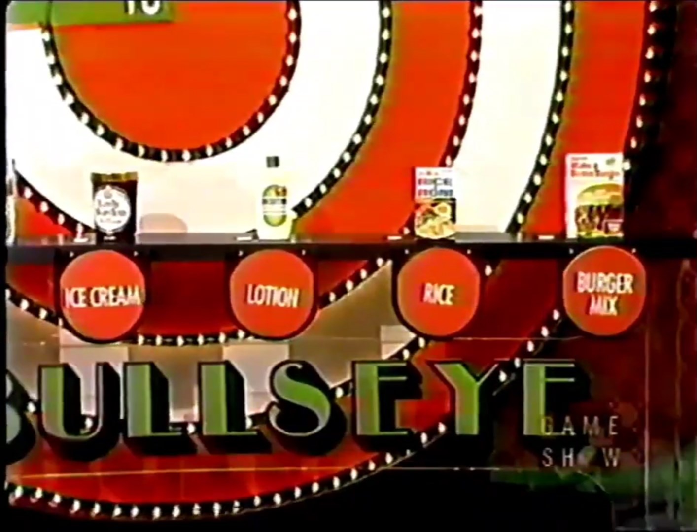 Display of four grocery products on a game show set, labeled 'Ice Cream', 'Lotion', 'Rice', and 'Burger Mix', with a prominent bullseye design in the background.