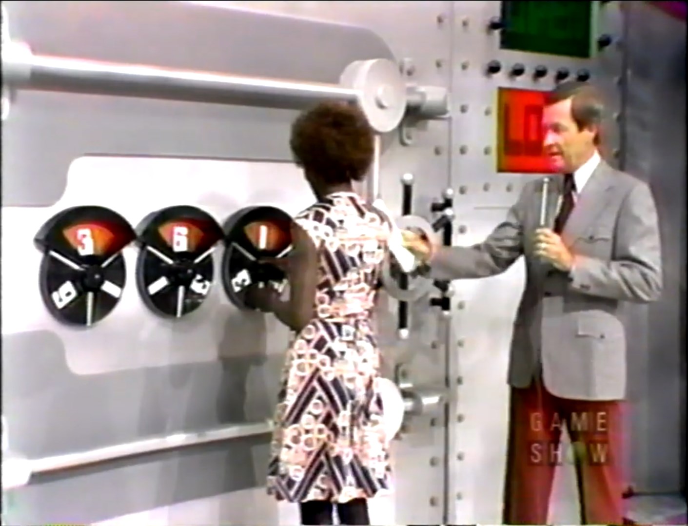 A contestant locks in a combination on a game show featuring a large safe, with Bob Barker explaining the rules.