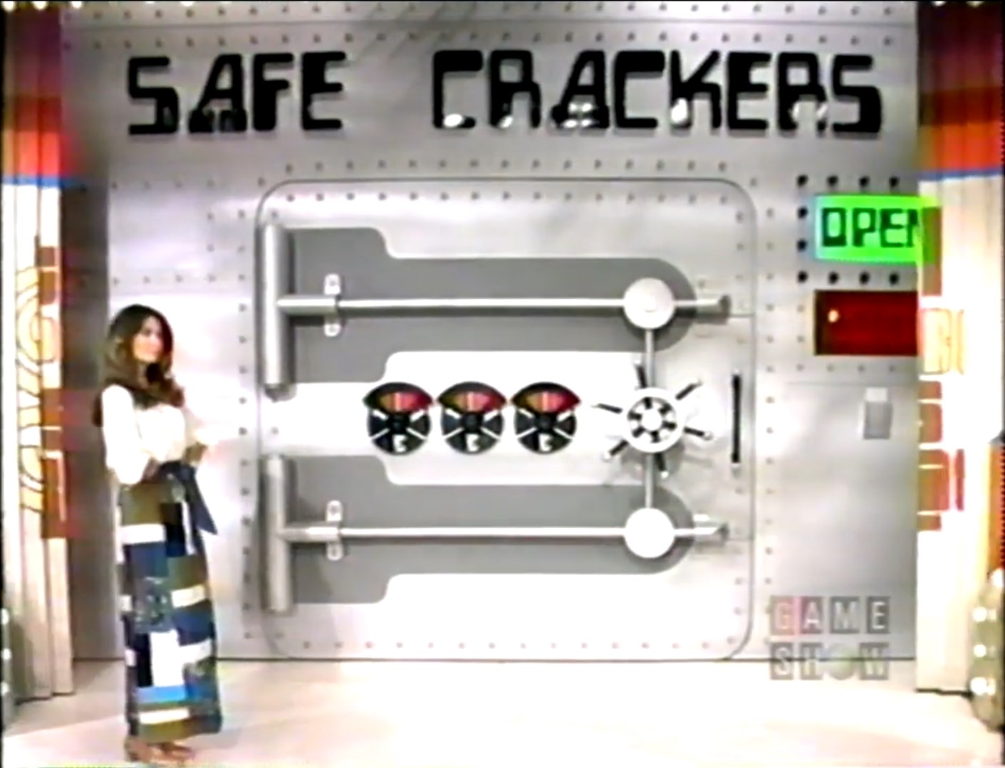 A model stands beside a large safe labeled 'SAFE CRACKERS' with the door in an open position, revealing various prize wheels.