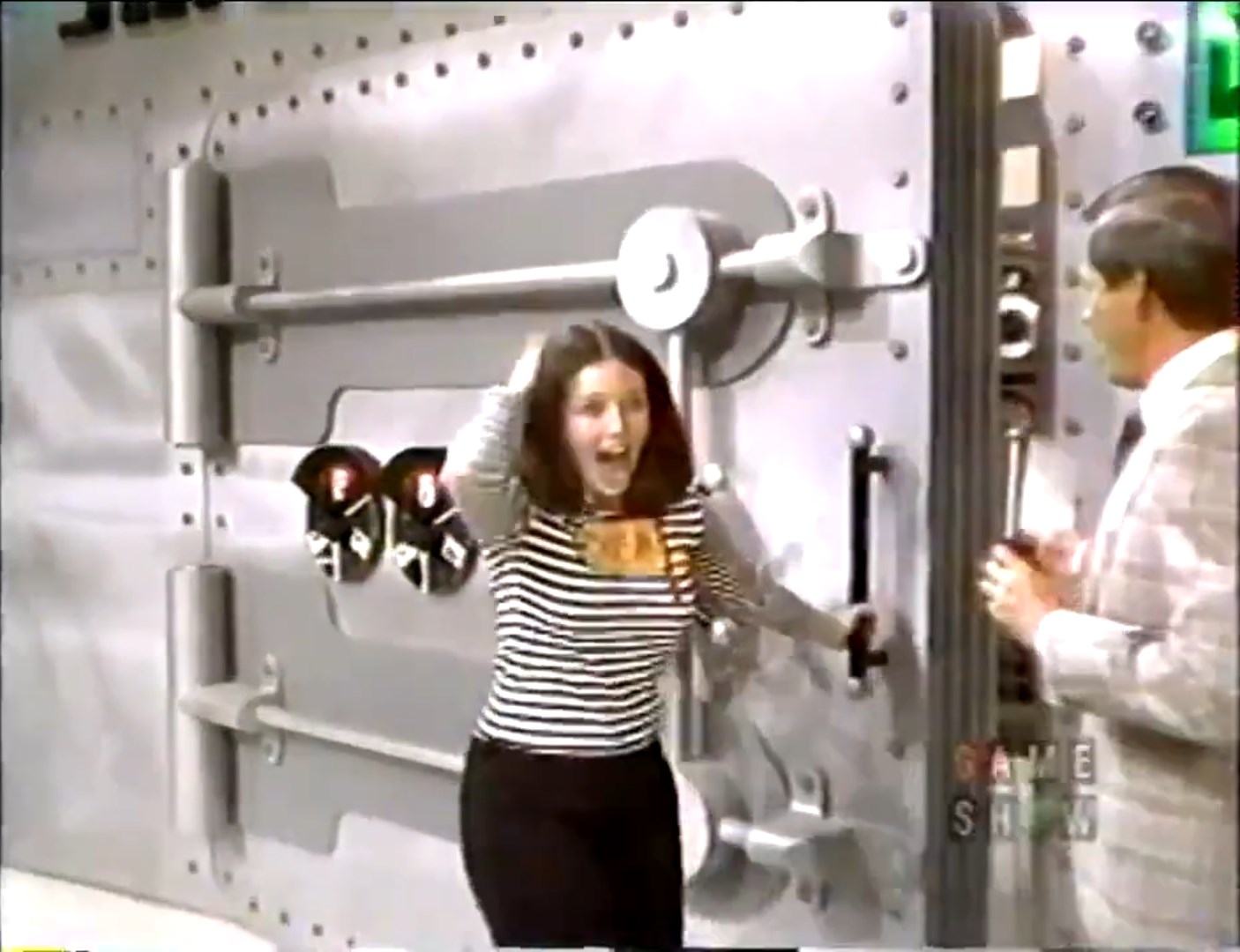 A contestant joyfully reacts as a large safe is opened on The Price is Right, with a host standing beside her.