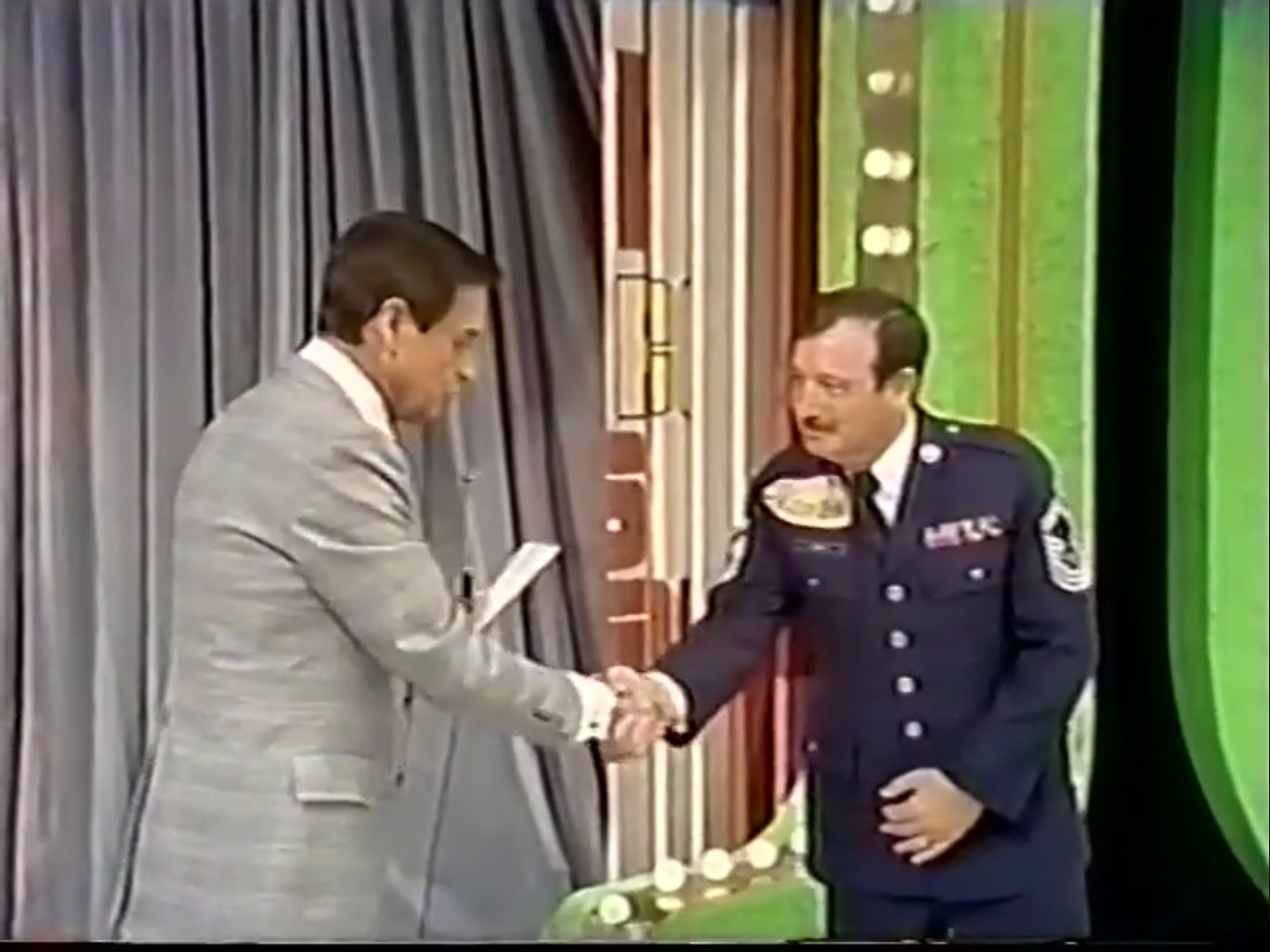 Bob Barker shakes hands with a contestant dressed in a military uniform on the set of The Price is Right.