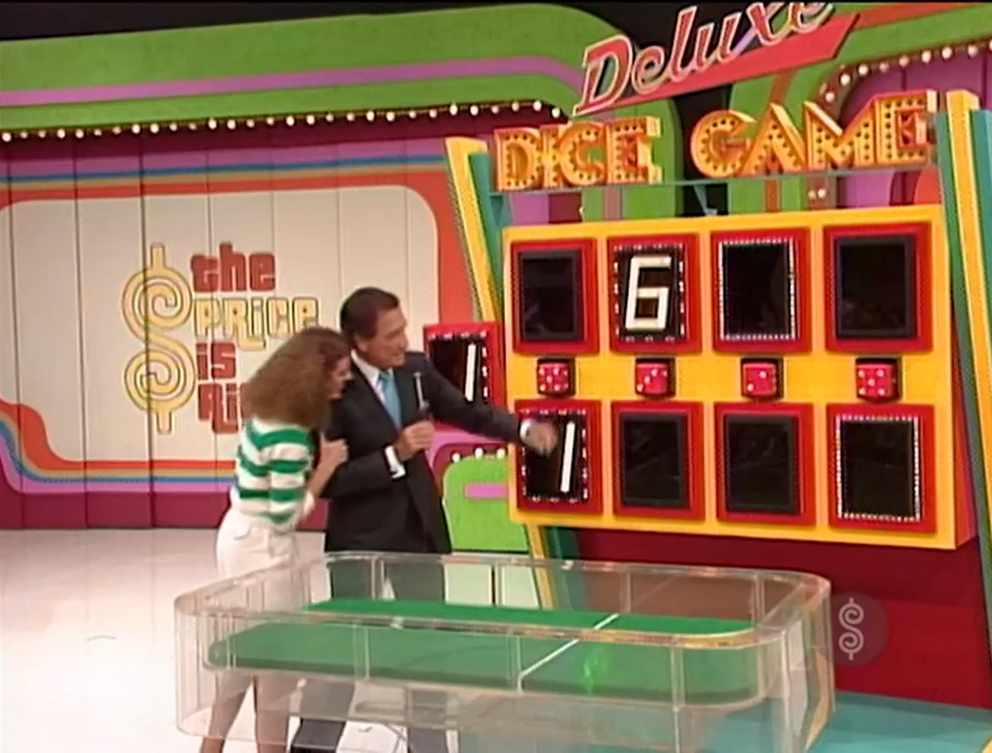 Contestant and host celebrate during the Deluxe Dice Game on 'The Price is Right', with a colorful game board displaying a six.