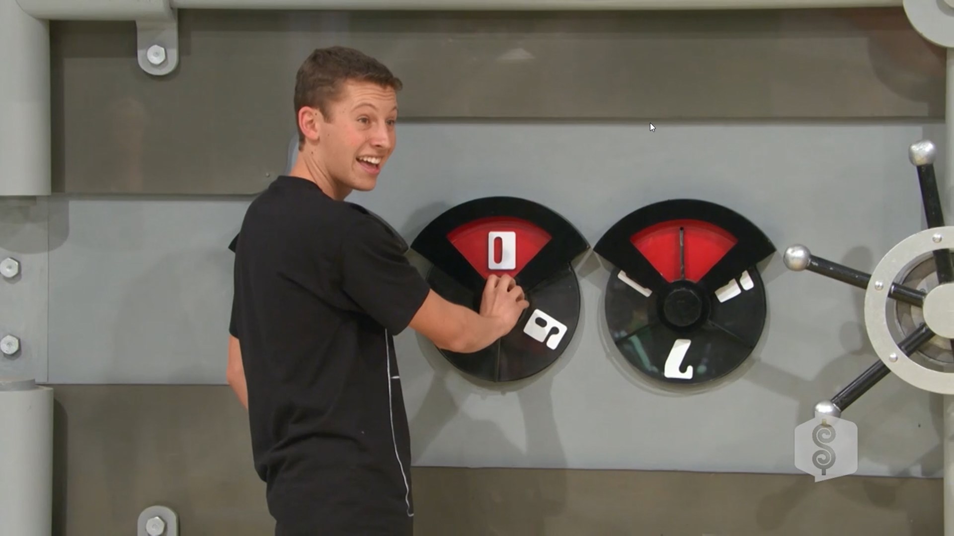 A contestant smiles while turning the dial on a game show safe, attempting to guess the correct combination.