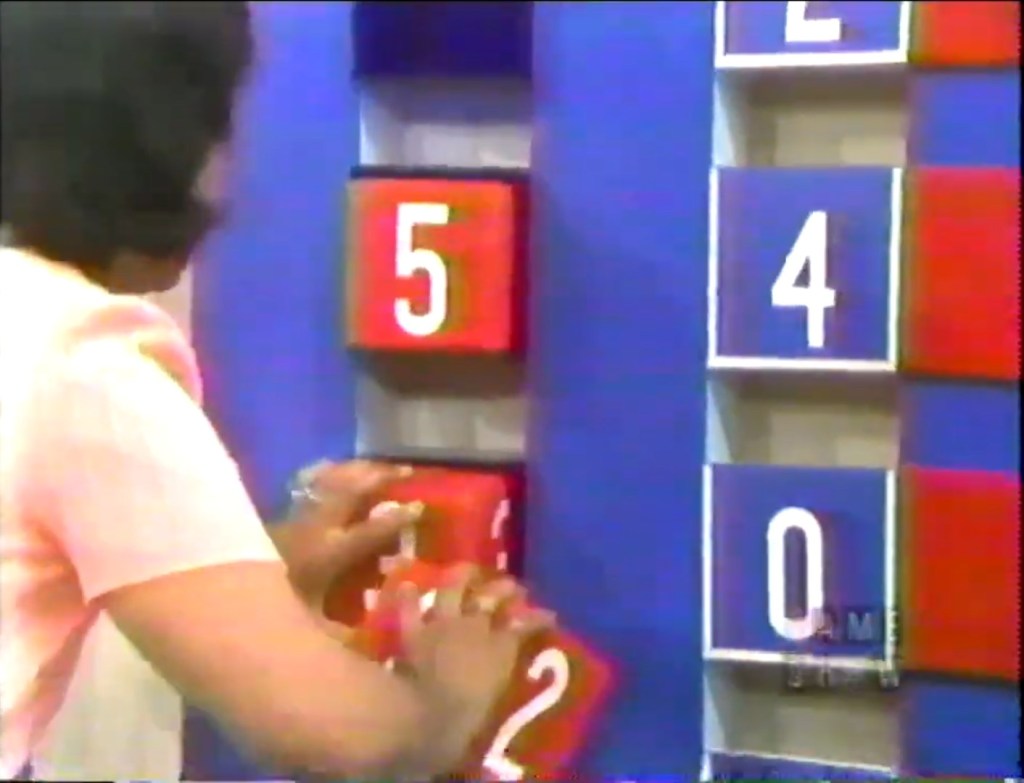A contestant placing numbered blocks on a game board in the Switcheroo game on The Price is Right.