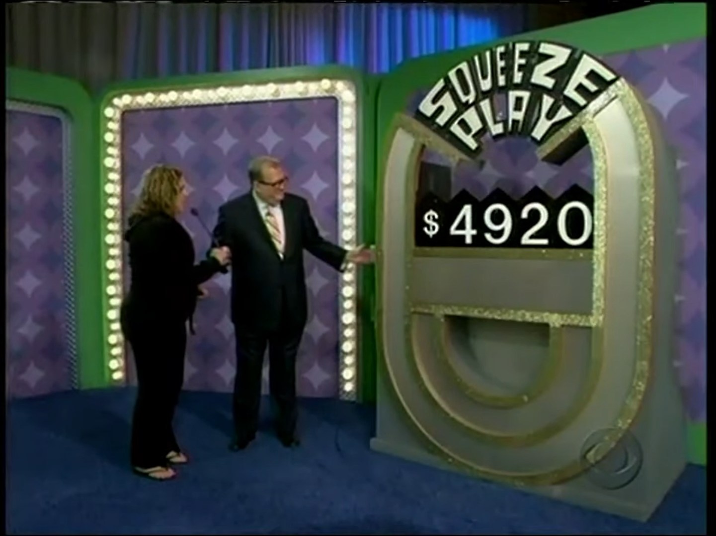 A contestant and host presenting the Squeeze Play game display showing a prize price of 20.