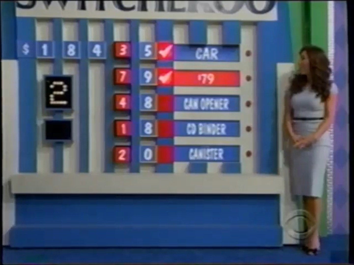A game board for Switcheroo on The Price is Right, featuring various prizes with missing numbers and a female contestant alongside.