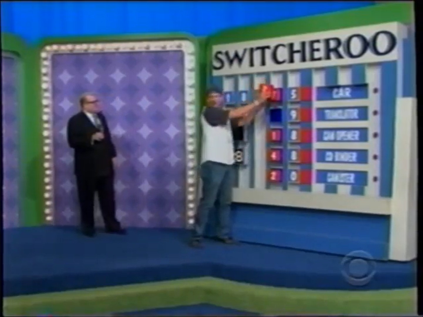 A contestant participating in the Switcheroo game on The Price is Right, adjusting blocks on the game board displaying various prizes including a car, a tractor, a can opener, and a ganner.