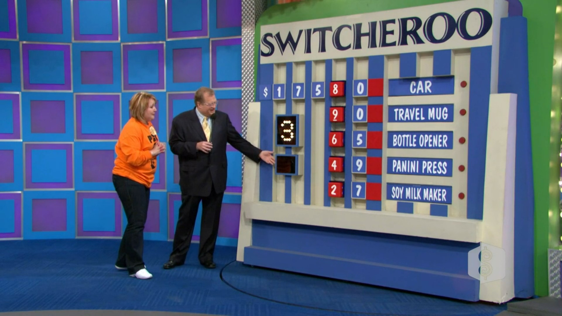 A contestant plays the Switcheroo game on The Price is Right, standing next to the game board displaying incomplete prices for various prizes, including a car and small items.
