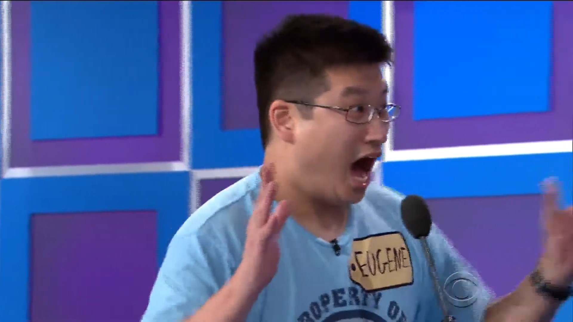 Contestant Eugene expresses excitement during a game on a colorful stage.