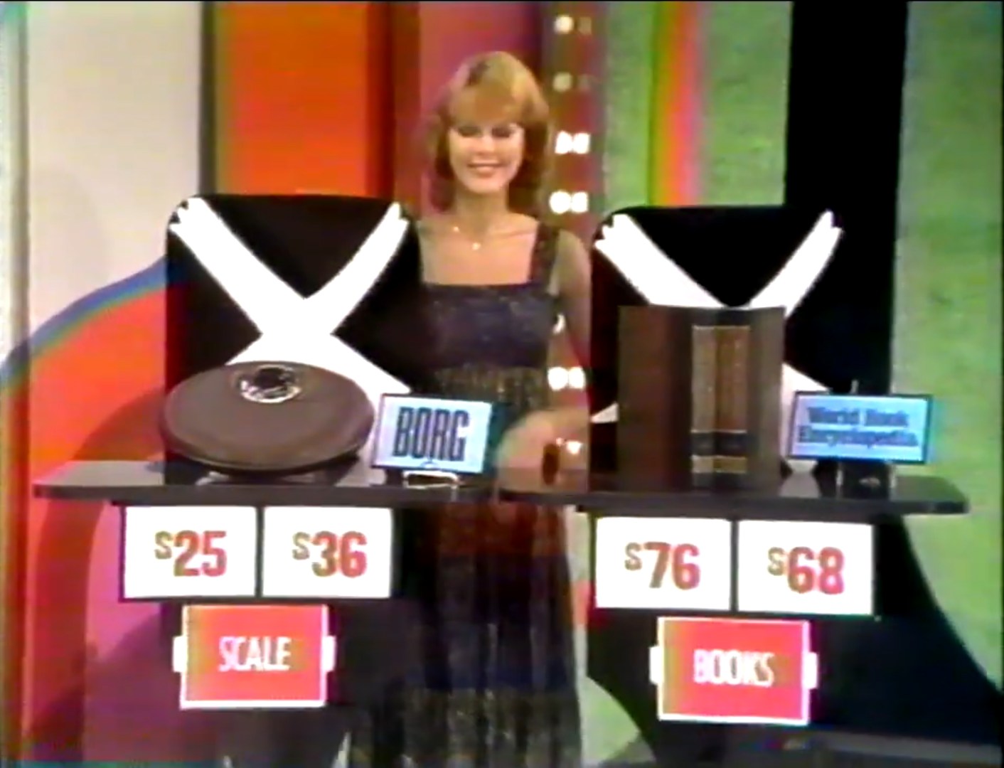 A game show contestant stands next to two prize displays featuring a scale priced at  or  and a set of encyclopedias priced at  or , with X marks visible on the display boards.