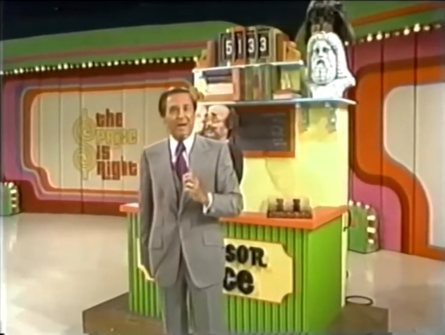 Bob Barker introduces the Professor Price game on The Price is Right, with a colorful set and a puppet behind him.