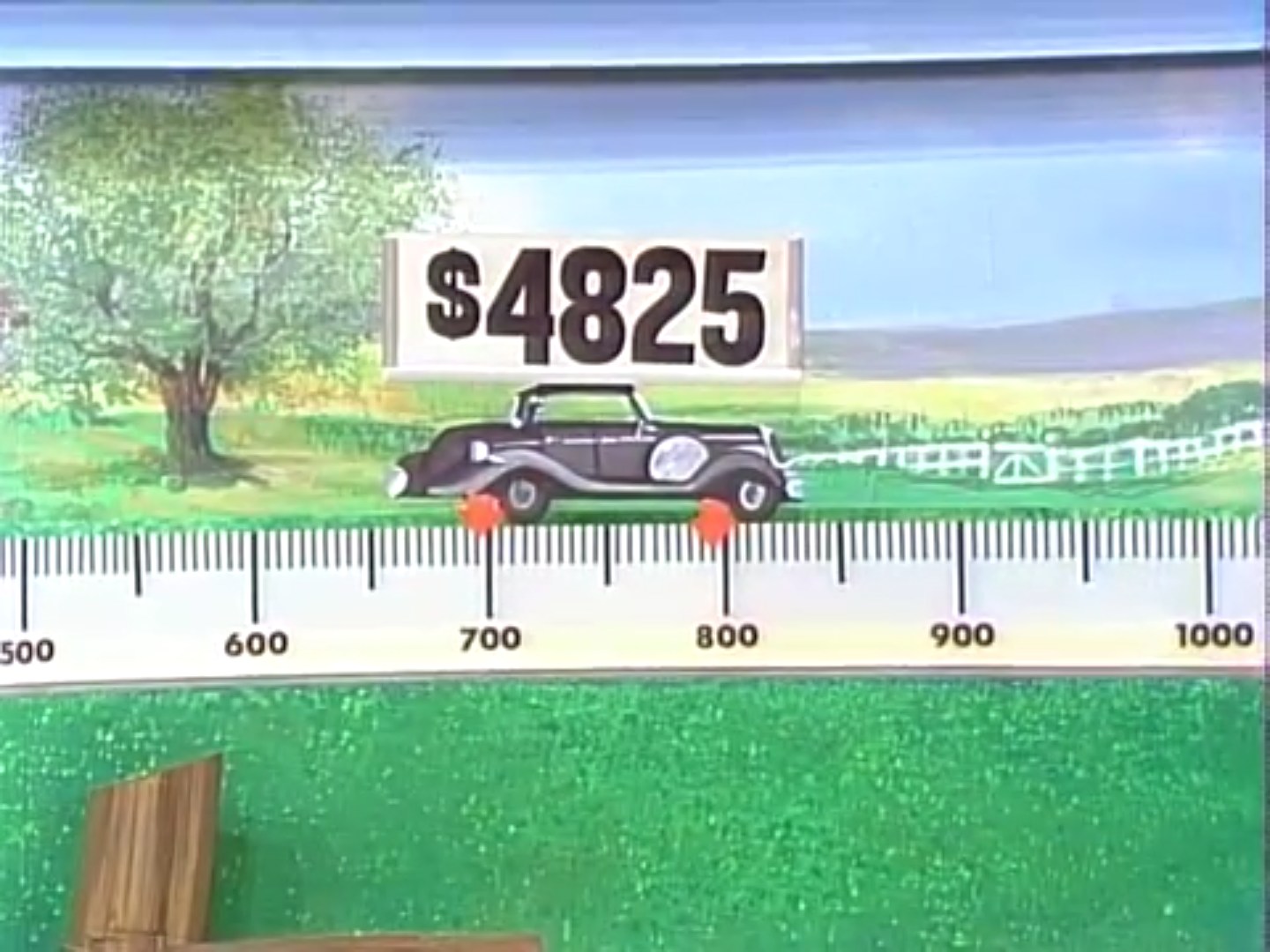 Close-up of a game board from The Price is Right showing two cars with prices: 30 for the base model and 25 for the model with options. A pointer indicates a range on a scale.