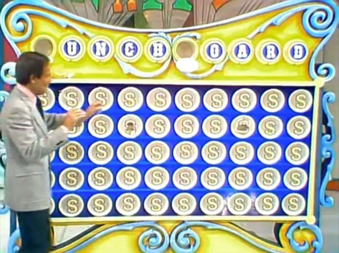A television host demonstrates the Punch a Bunch game board featuring numbered holes and dollar signs.
