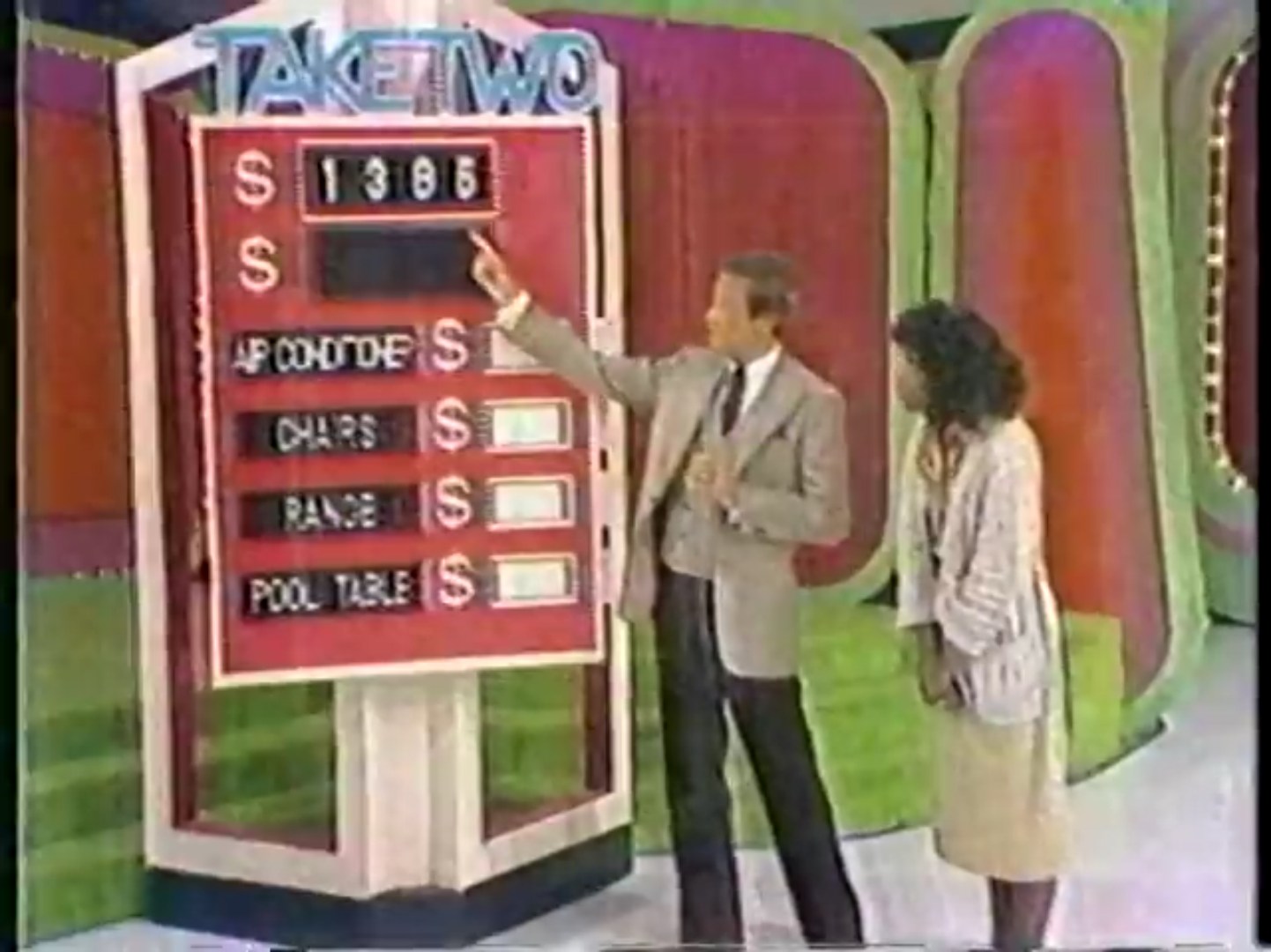 A host points to the target price of 85 on a game board for 'Take Two' while a contestant looks on.