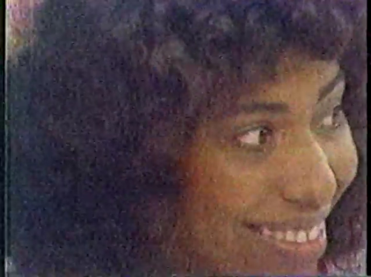 Close-up of a smiling woman with curly hair, showing enthusiasm while participating in a game.