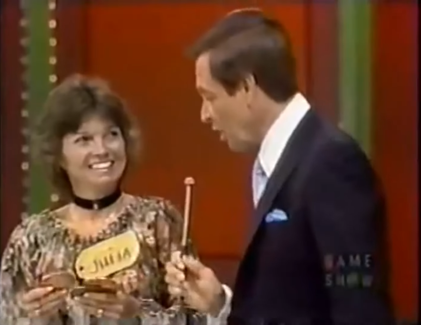 A contestant named Julia smiles while holding three oversized 'pennies' during a segment of Penny Ante on The Price is Right.
