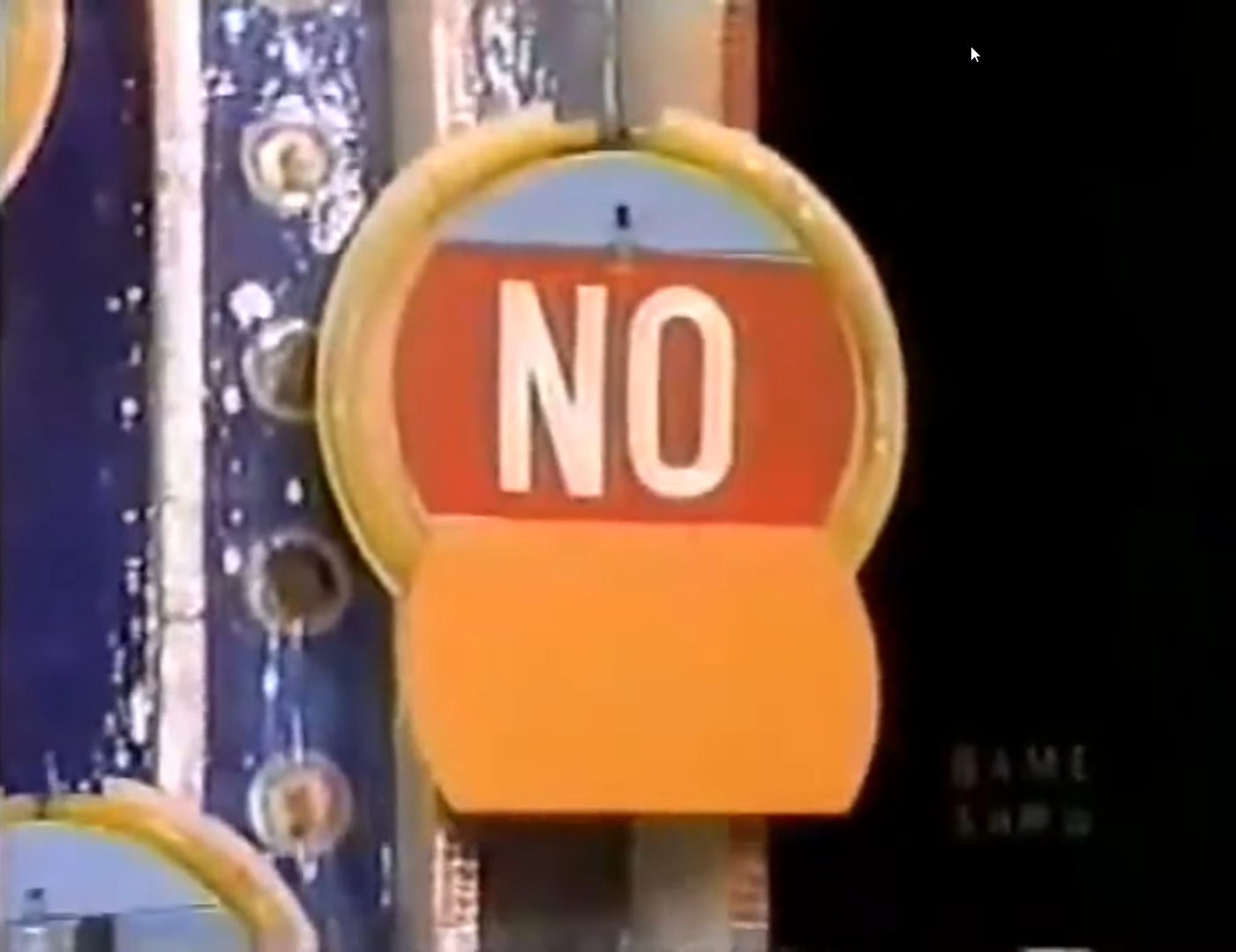 A game show set piece featuring a sign displaying the word 'NO' in bold letters, with vibrant colors and a distinct design.