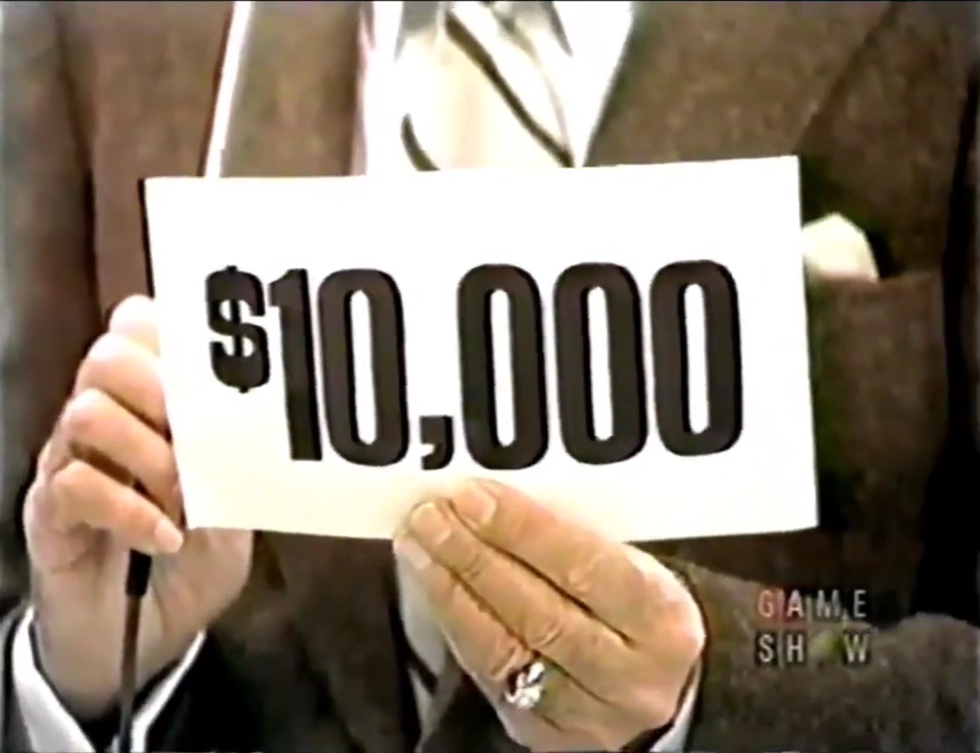 ,000 cash prize displayed on a sign held by a game show host.