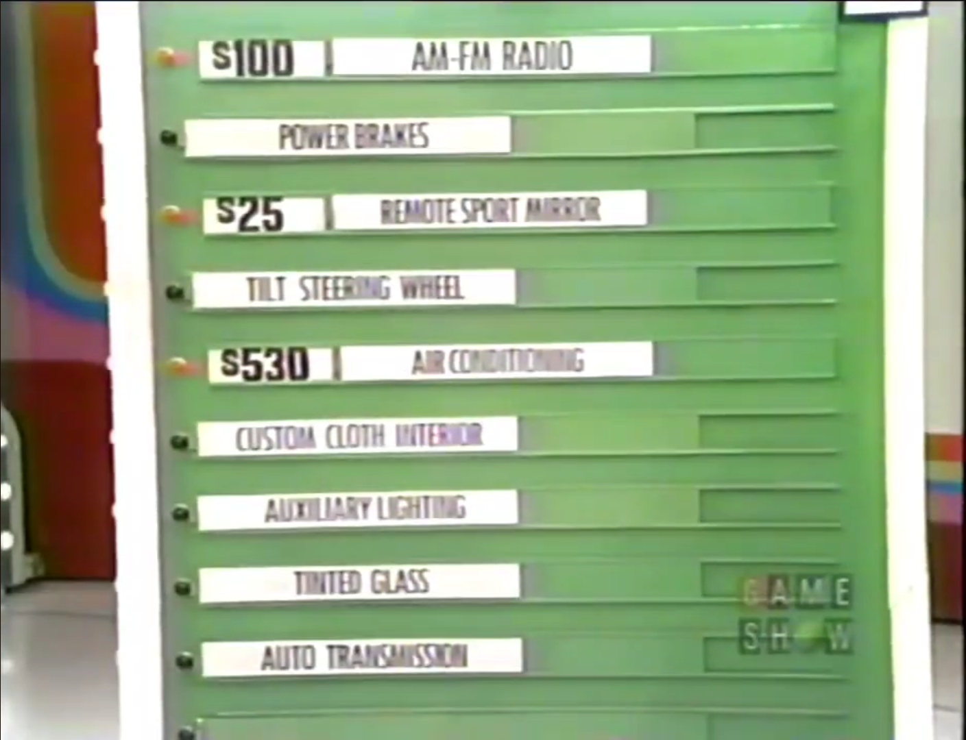 A game board displaying option prices for a car game, featuring items like 'AM-FM Radio' priced at 0, and 'Air Conditioning' at 0.