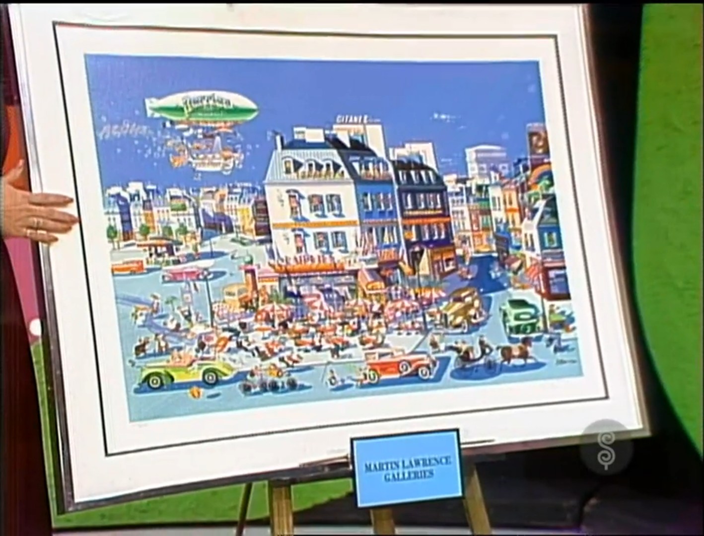 A colorful artwork depicting a bustling street scene, featuring vintage cars, pedestrians, and a blimp overhead. The framed artwork is attributed to Martin Lawrence Galleries.