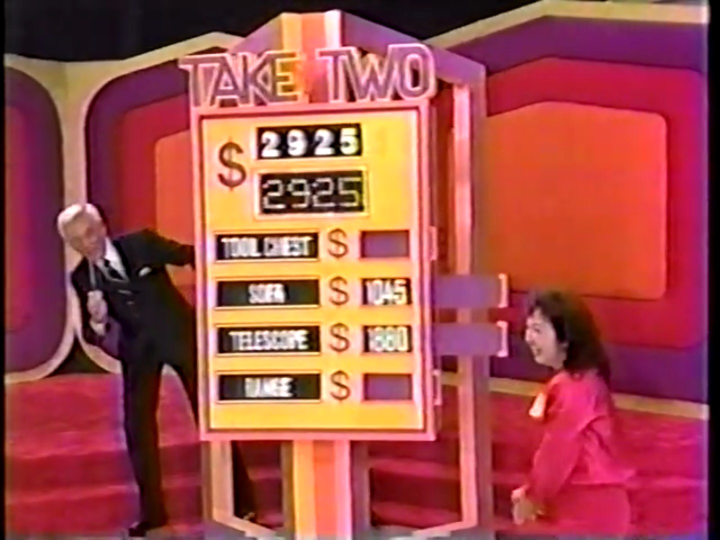 A contestant smiles while playing the Take Two game on The Price is Right, with prices displayed for prizes including a tool chest, sofa, telescope, and range.